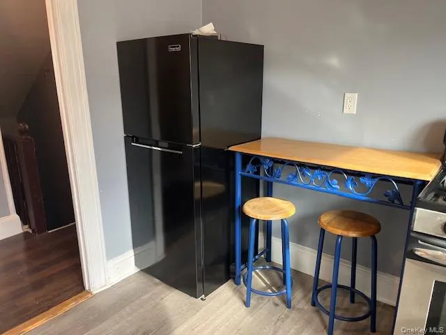 Kitchen with wooden counters, a kitchen breakfast bar, hardwood / wood-style flooring, gas stove, and black fridge Kitchen with wooden counters, a kitchen breakfast bar, hardwood / wood-style flooring, gas stove, and black fridge