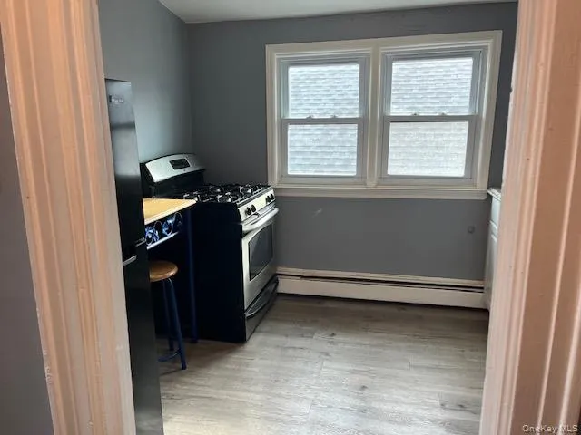 Kitchen with a baseboard heating unit, gas range, and light hardwood / wood-style floors Kitchen with a baseboard heating unit, gas range, and light hardwood / wood-style floors