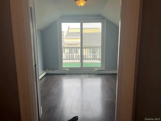 Bonus room with lofted ceiling, dark hardwood / wood-style flooring, and baseboard heating Bonus room with lofted ceiling, dark hardwood / wood-style flooring, and baseboard heating