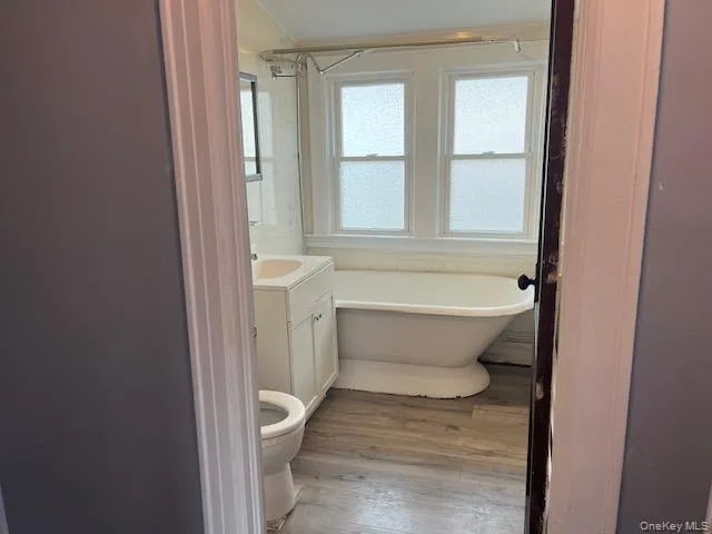 Bathroom featuring hardwood / wood-style flooring, vanity, toilet, and a tub Bathroom featuring hardwood / wood-style flooring, vanity, toilet, and a tub
