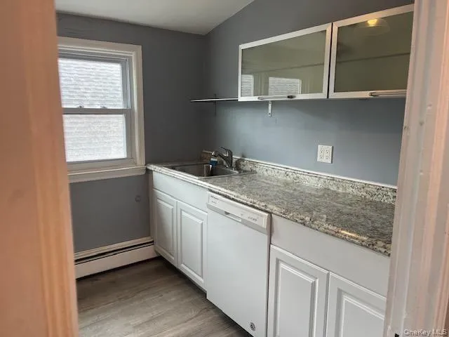 Kitchen with sink, white cabinets, light hardwood / wood-style floors, white dishwasher, and baseboard heating Kitchen with sink, white cabinets, light hardwood / wood-style floors, white dishwasher, and baseboard heating