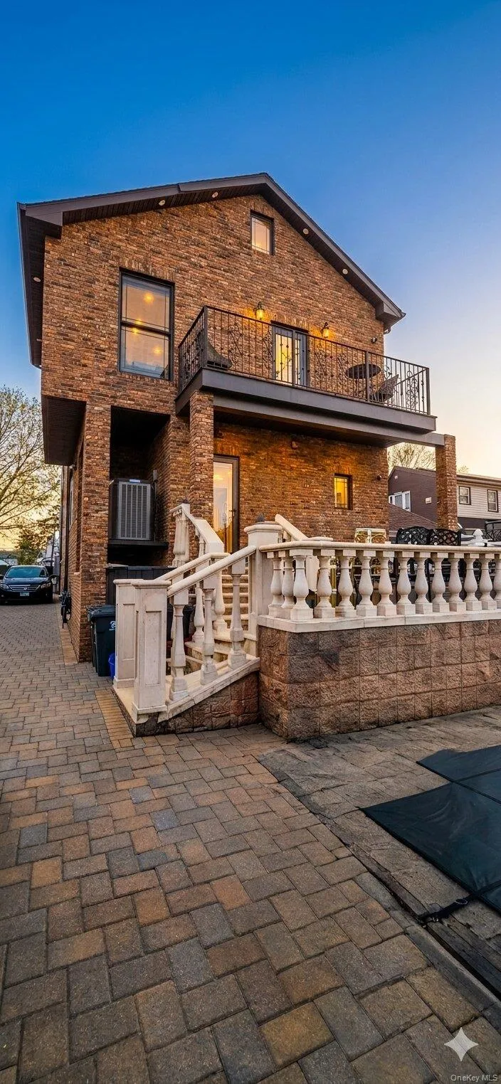Brick exterior featuring a gabled roofline, second-story balcony with iron railing, and stone balustrade. A.I Enchanced Brick exterior featuring a gabled roofline, second-story balcony with iron railing, and stone balustrade. A.I Enchanced