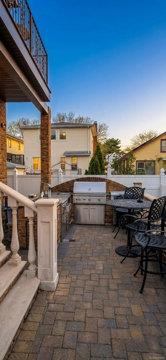 Brick paver patio featuring a built-in outdoor kitchen with stainless steel appliances, a brick surround, and a balustrade staircase. A.I Enchanced Brick paver patio featuring a built-in outdoor kitchen with stainless steel appliances, a brick surround, and a balustrade staircase. A.I Enchanced