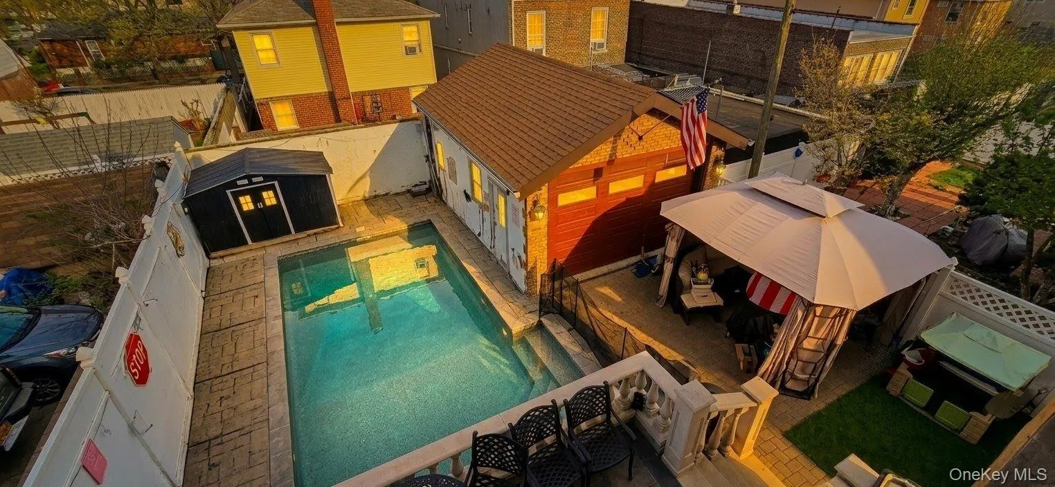 Private outdoor area featuring an in-ground swimming pool, a detached garage with a red door, and a black storage shed. A.I Enchanced Private outdoor area featuring an in-ground swimming pool, a detached garage with a red door, and a black storage shed. A.I Enchanced