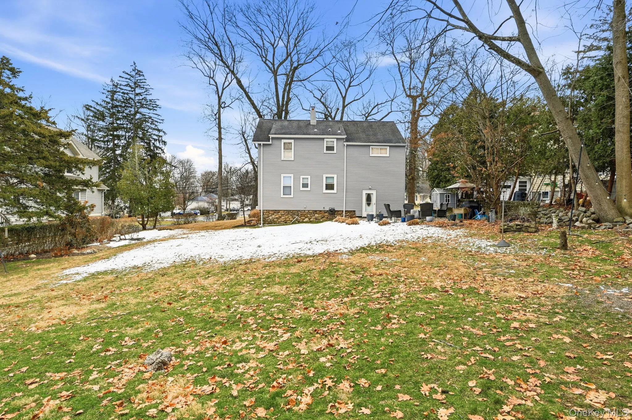 Snow covered back of property with a lawn, a patio, and a chimney Snow covered back of property with a lawn, a patio, and a chimney