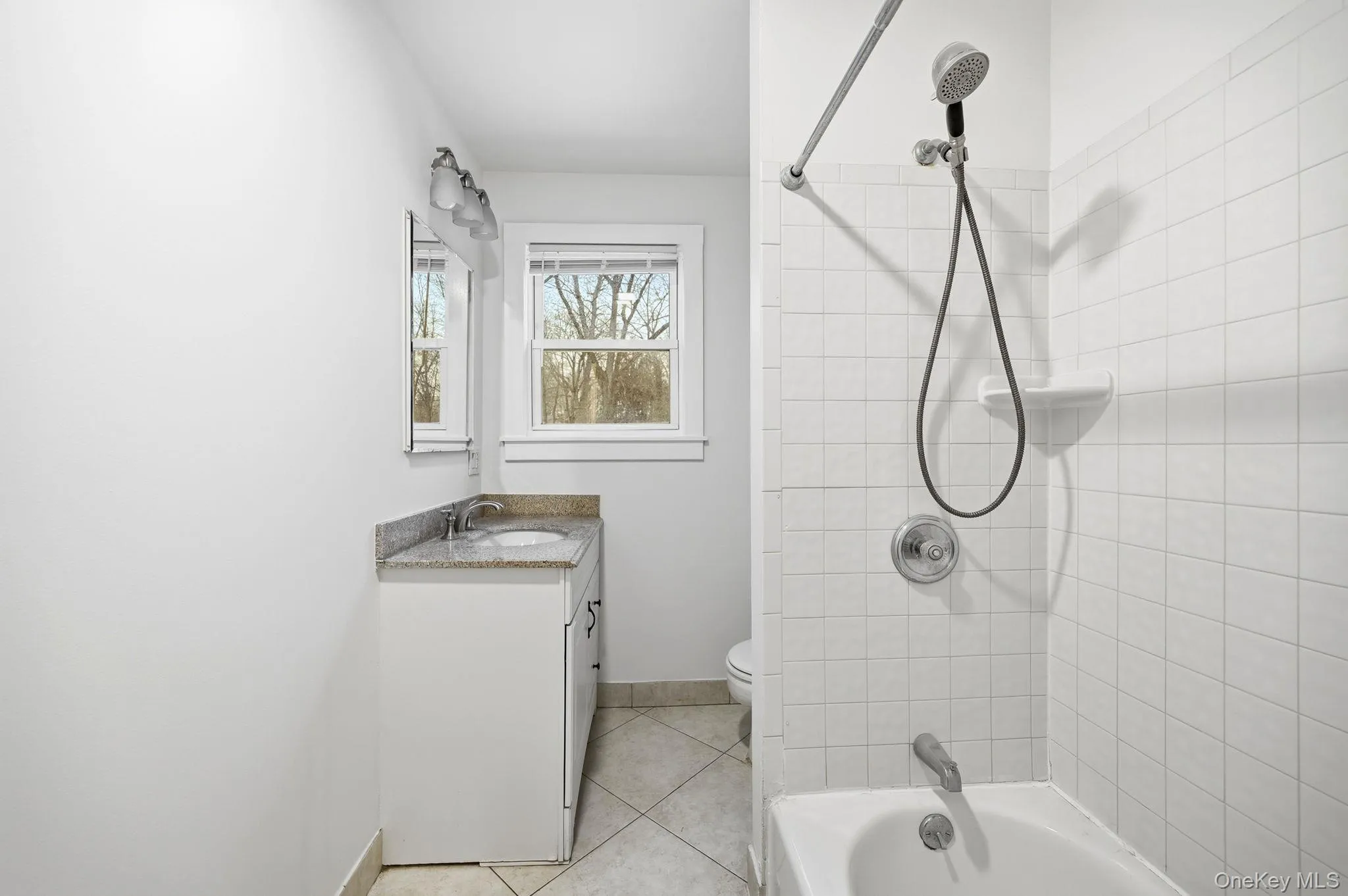 Bathroom with bathing tub / shower combination, vanity, and light tile patterned floors Bathroom with bathing tub / shower combination, vanity, and light tile patterned floors