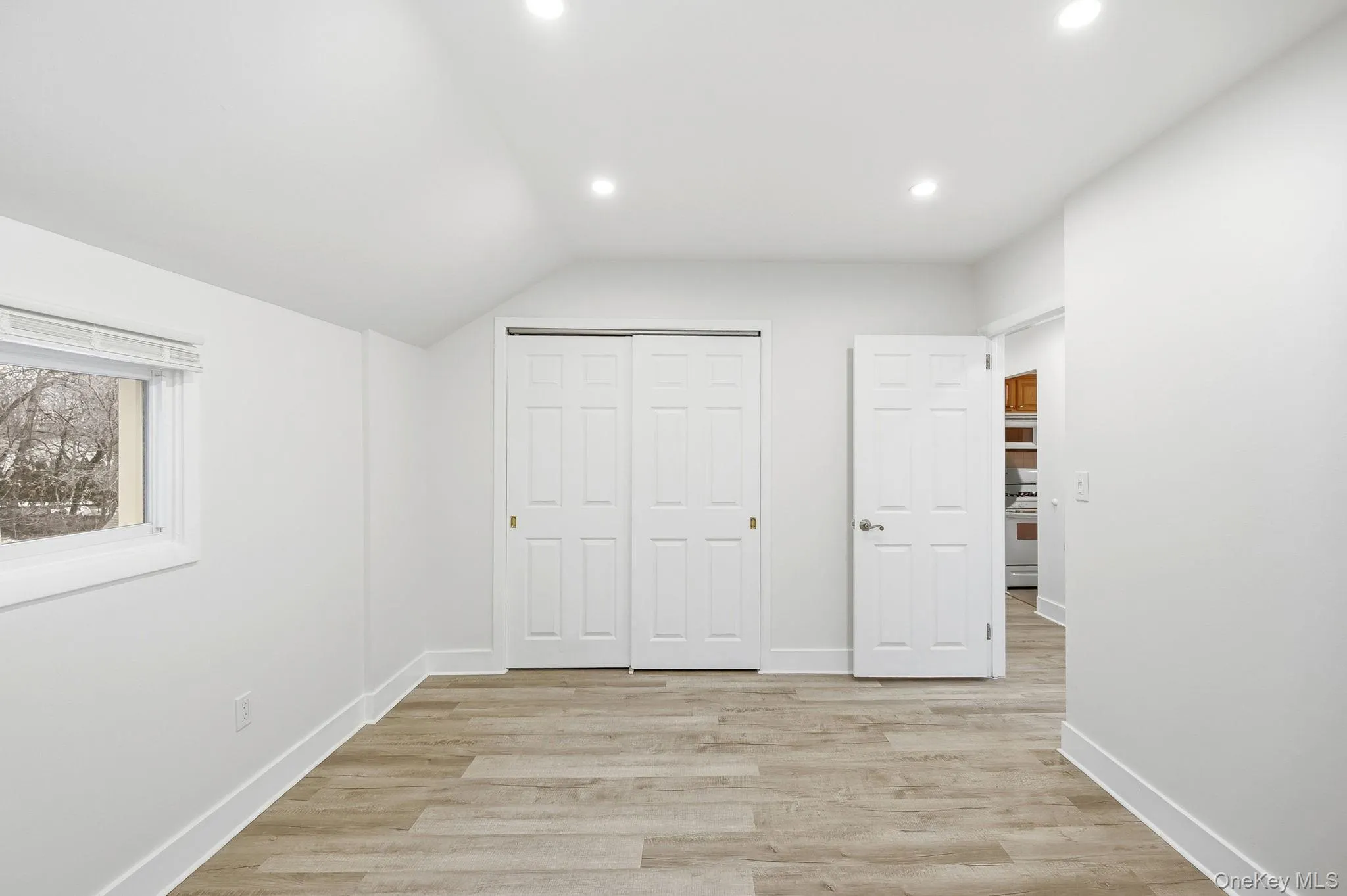 Unfurnished bedroom with light wood finished floors, recessed lighting, a closet, and vaulted ceiling Unfurnished bedroom with light wood finished floors, recessed lighting, a closet, and vaulted ceiling