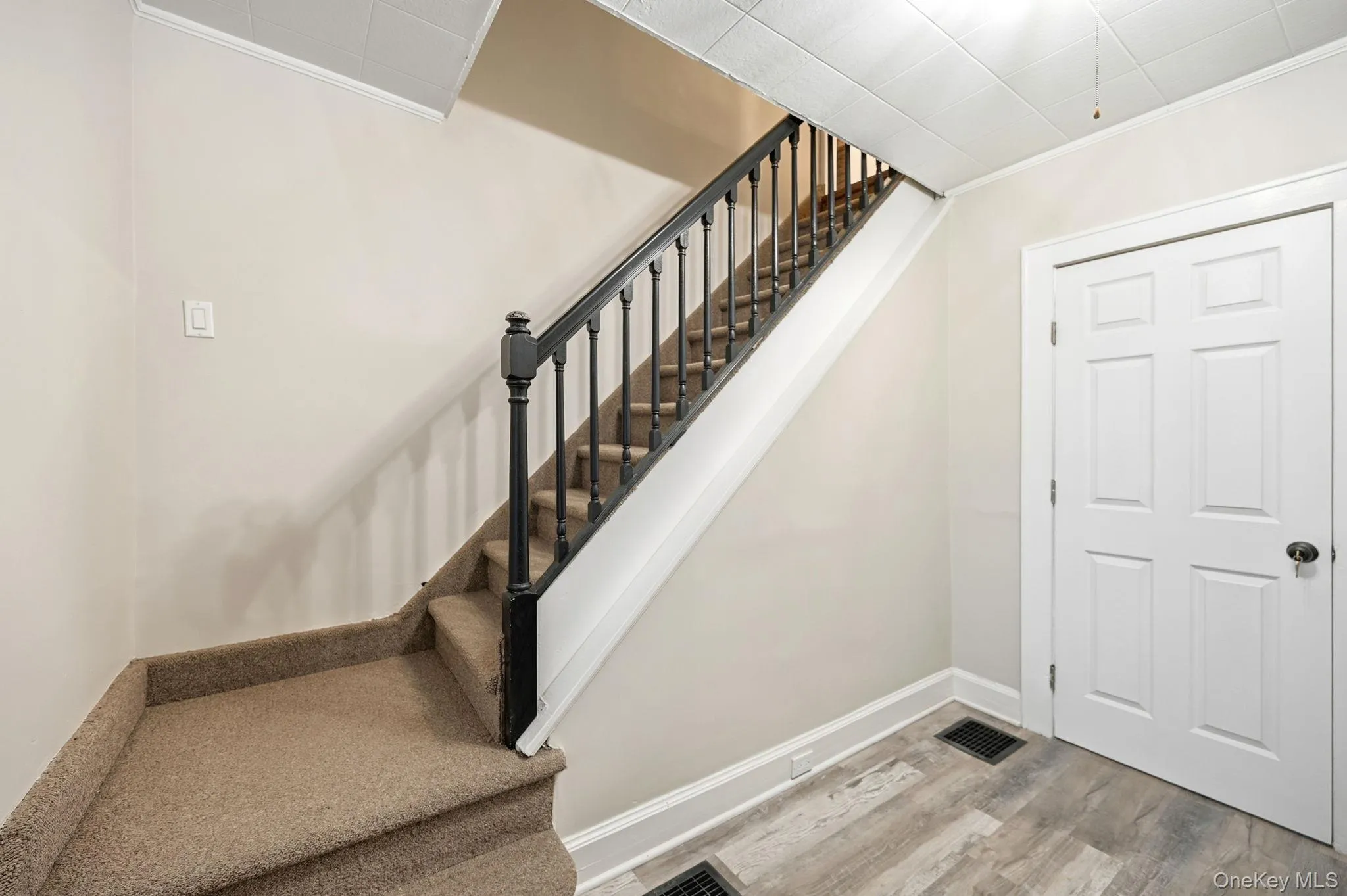 Stairs featuring wood finished floors and crown molding Stairs featuring wood finished floors and crown molding