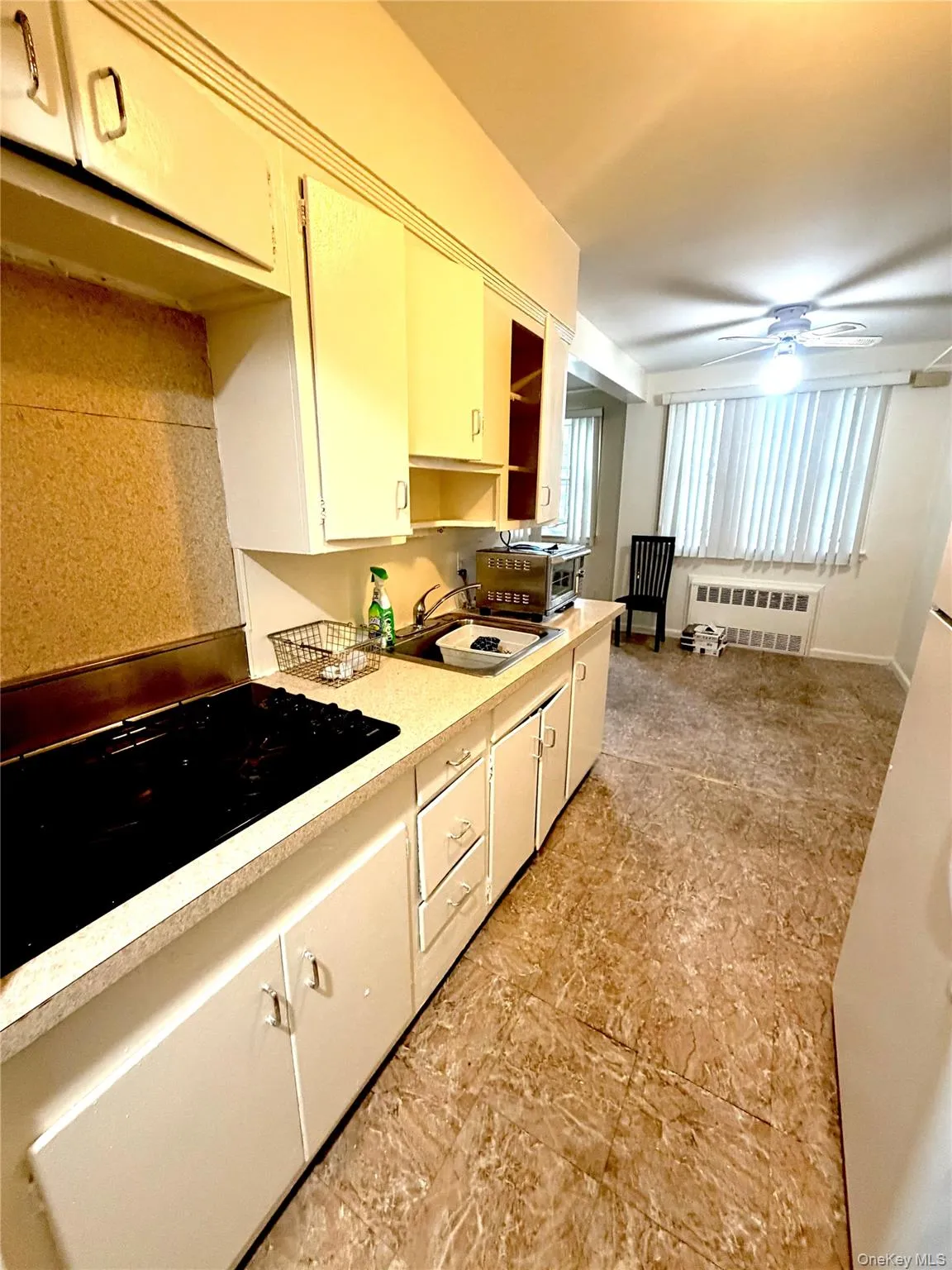 Kitchen area featuring white cabinetry, a built-in cooktop, and a double-basin sink Kitchen area featuring white cabinetry, a built-in cooktop, and a double-basin sink
