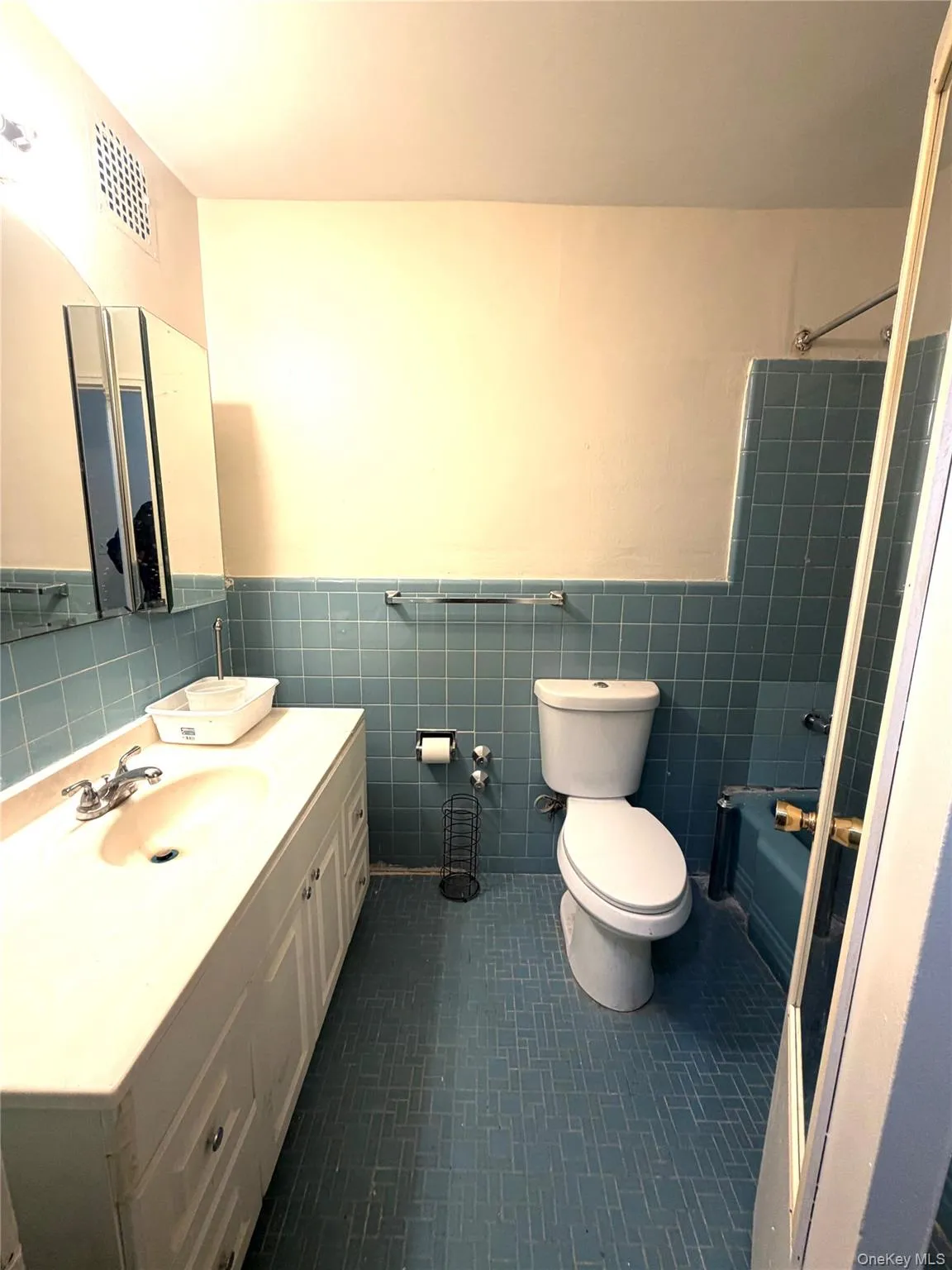 Bathroom featuring blue tile flooring, a white vanity with integrated sink, and a mirrored medicine cabinet Bathroom featuring blue tile flooring, a white vanity with integrated sink, and a mirrored medicine cabinet