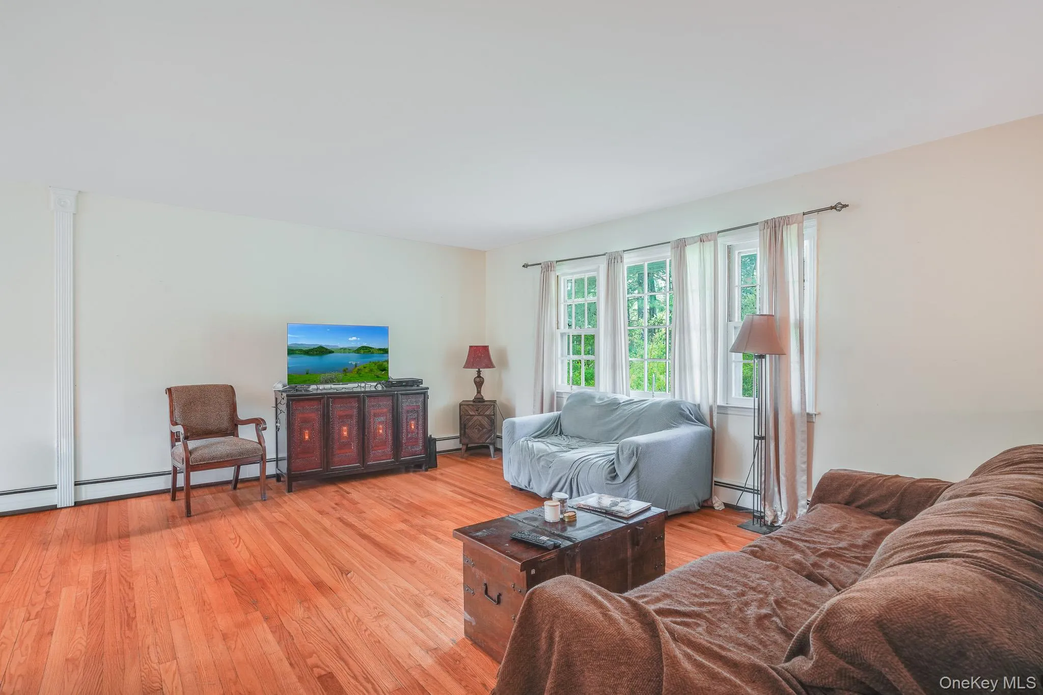 Living area featuring polished wood-finish flooring and multiple windows Living area featuring polished wood-finish flooring and multiple windows