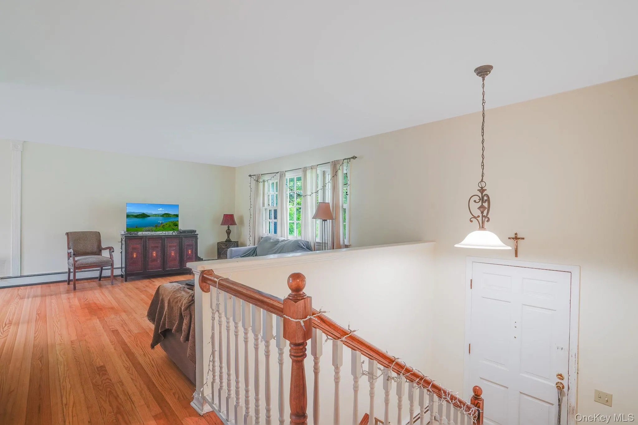 Hardwood flooring in a living area featuring a decorative console cabinet and bright windows Hardwood flooring in a living area featuring a decorative console cabinet and bright windows