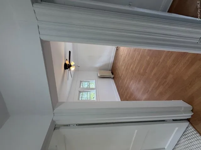 Interior room featuring wood-finish flooring, white walls, and a ceiling fan with integrated lighting Interior room featuring wood-finish flooring, white walls, and a ceiling fan with integrated lighting