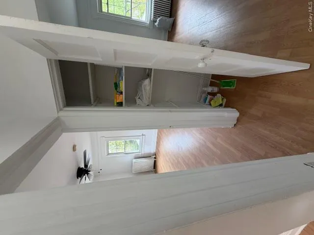 Interior closet with shelving, wood-finish flooring, white trim, and a partially open door Interior closet with shelving, wood-finish flooring, white trim, and a partially open door