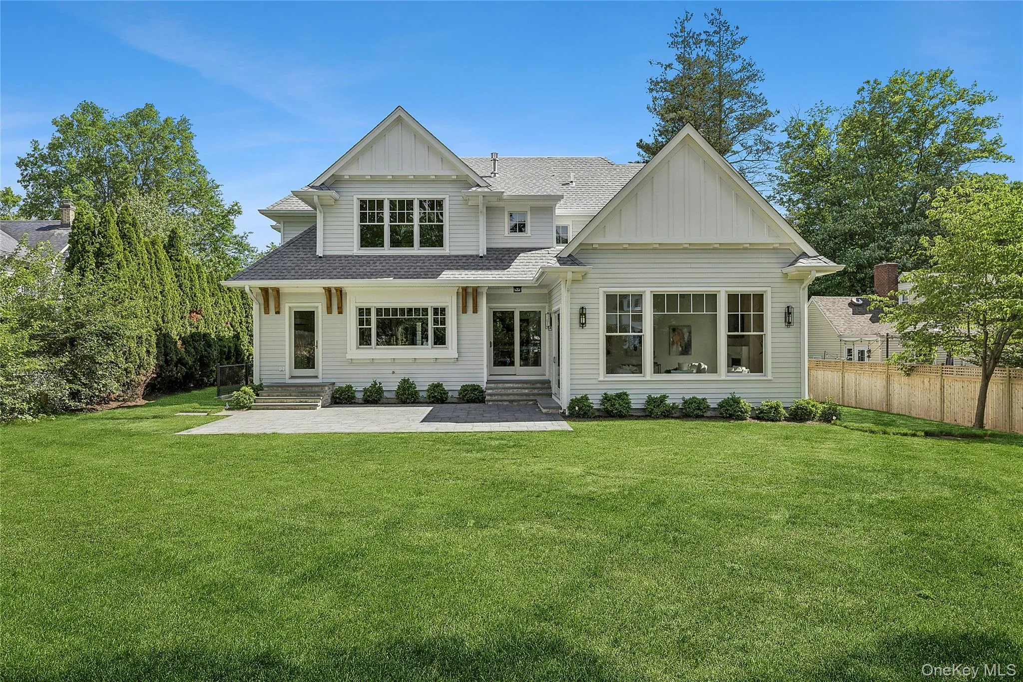 Expansive backyard featuring a manicured lawn, a large paver patio, and mature perimeter trees Expansive backyard featuring a manicured lawn, a large paver patio, and mature perimeter trees