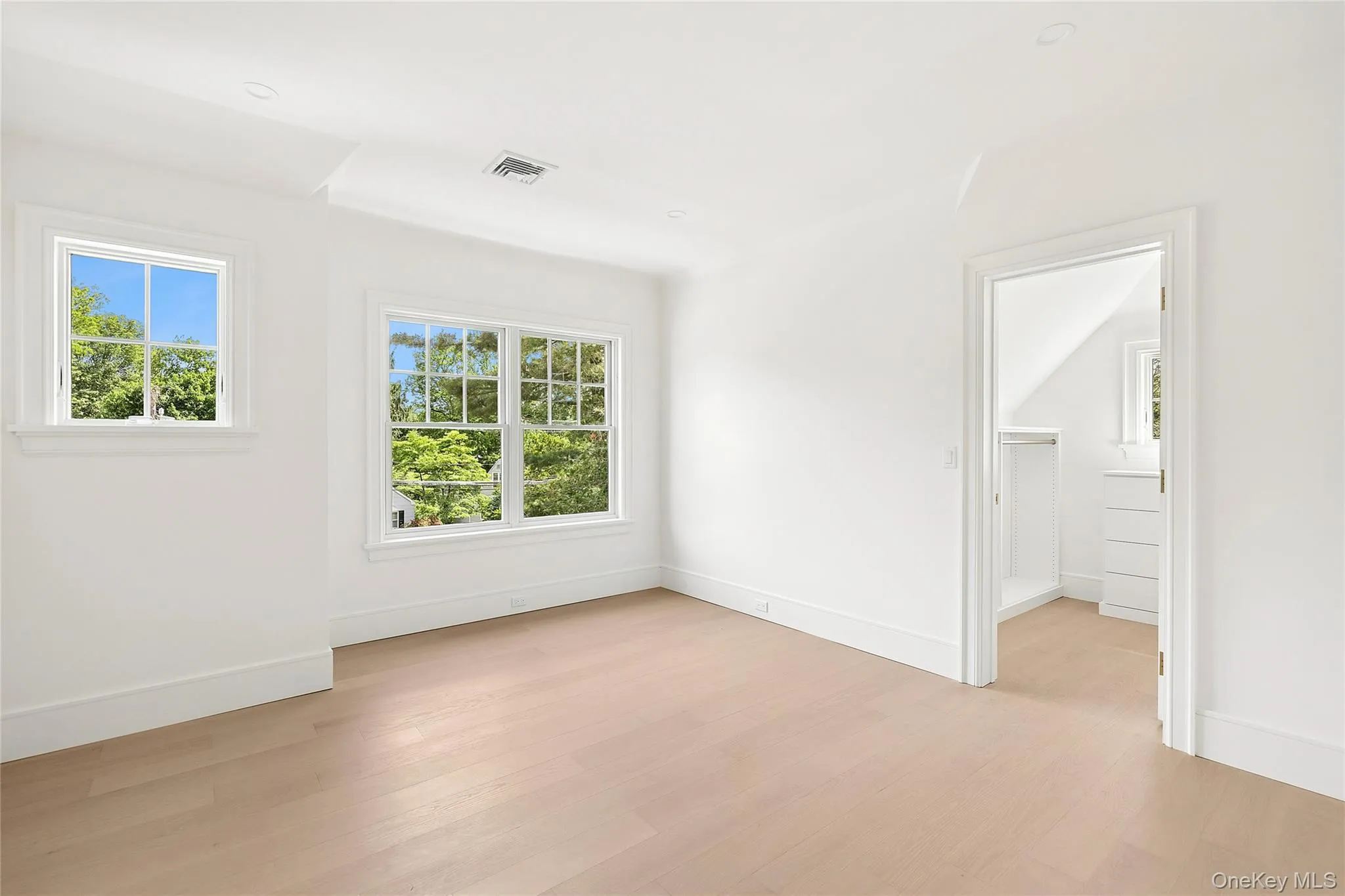 Bright room with wood-finish flooring, recessed lighting, and multiple windows Bright room with wood-finish flooring, recessed lighting, and multiple windows