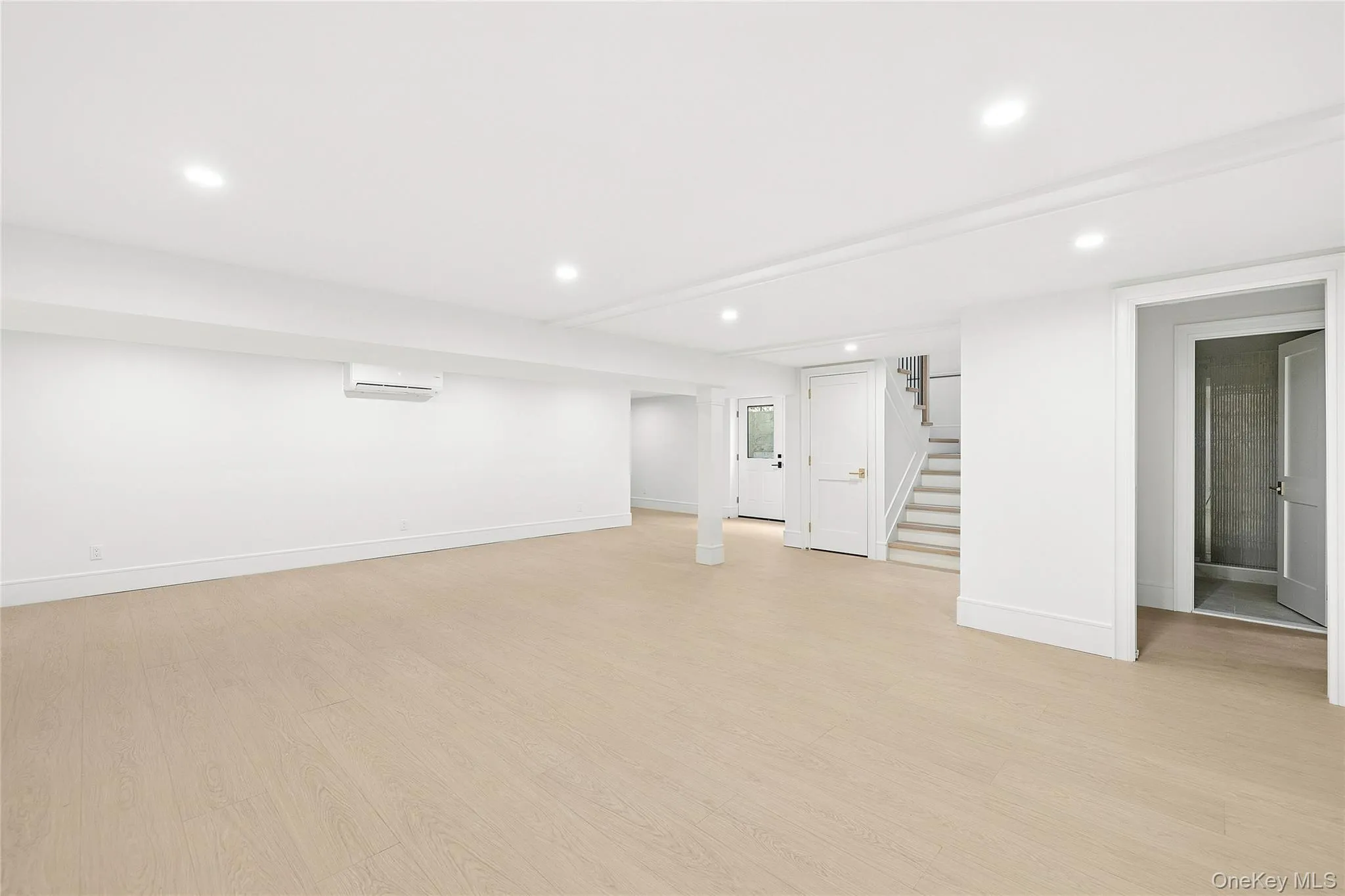 Spacious room featuring light wood-finish flooring, recessed lighting, and white baseboards Spacious room featuring light wood-finish flooring, recessed lighting, and white baseboards