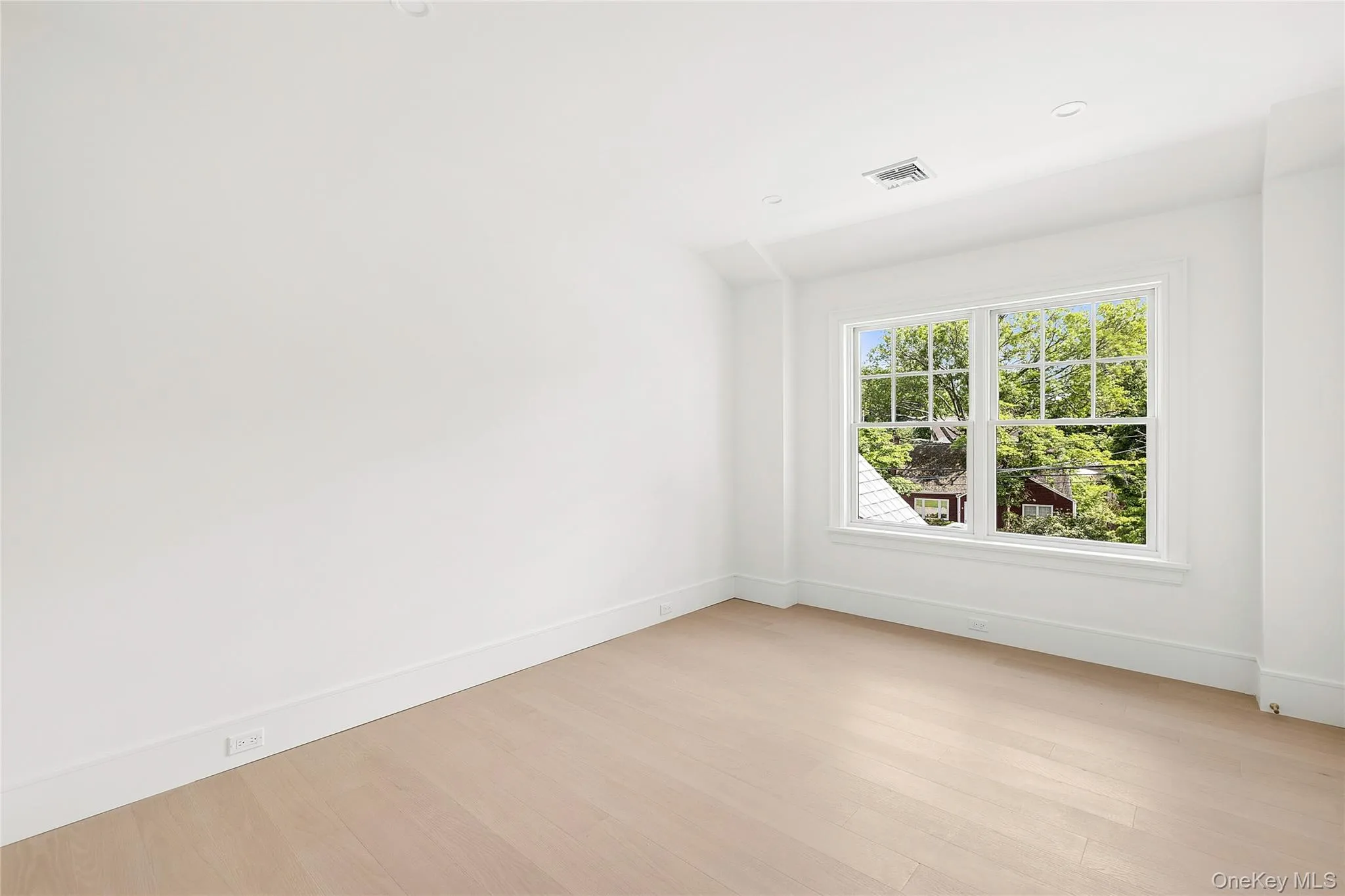 Bright interior space featuring a large window with multiple panes, light wood-finish flooring, white walls, and recessed lighting Bright interior space featuring a large window with multiple panes, light wood-finish flooring, white walls, and recessed lighting