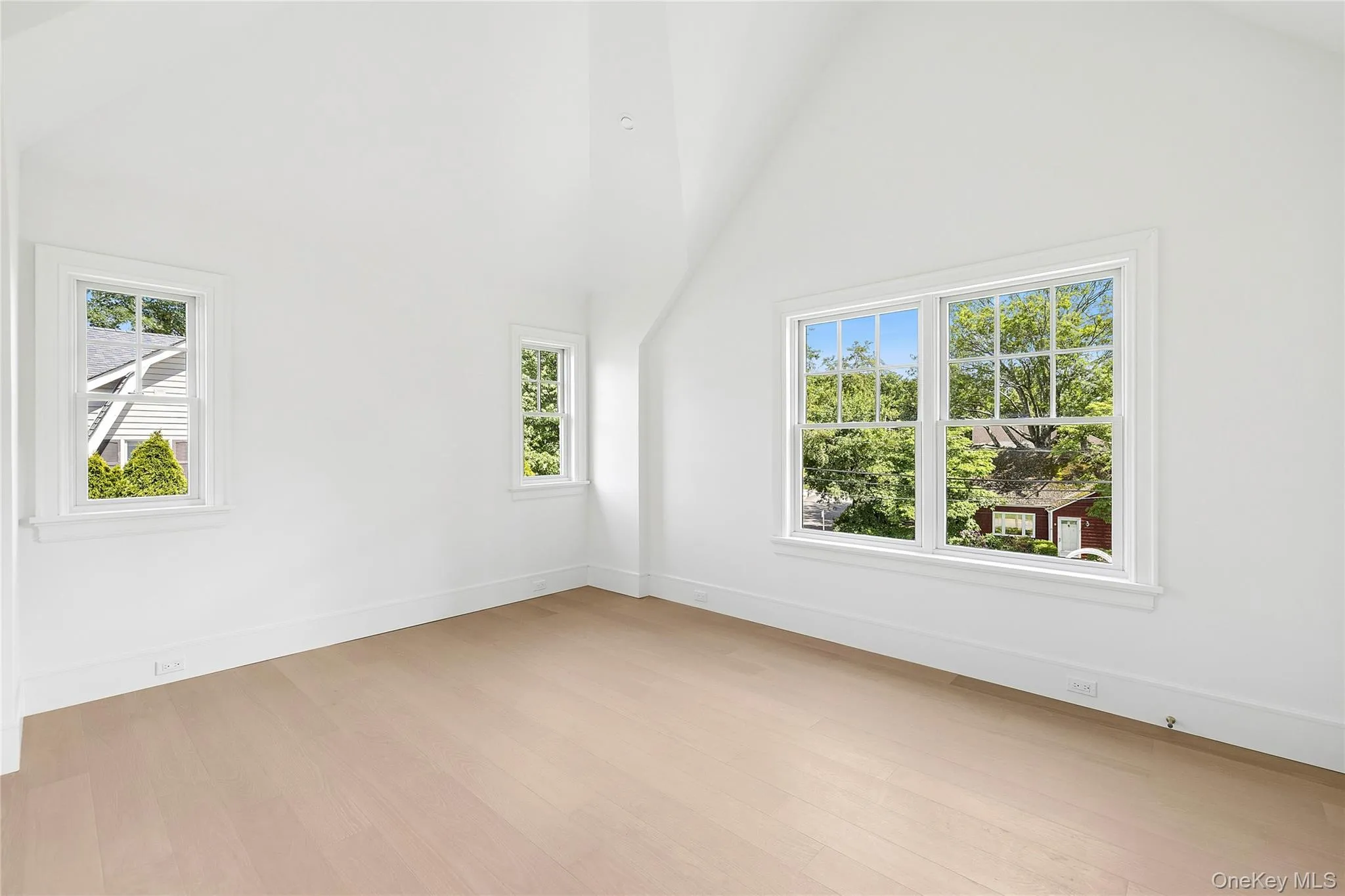 Room featuring light wood-finish flooring, white walls, and a vaulted ceiling Room featuring light wood-finish flooring, white walls, and a vaulted ceiling
