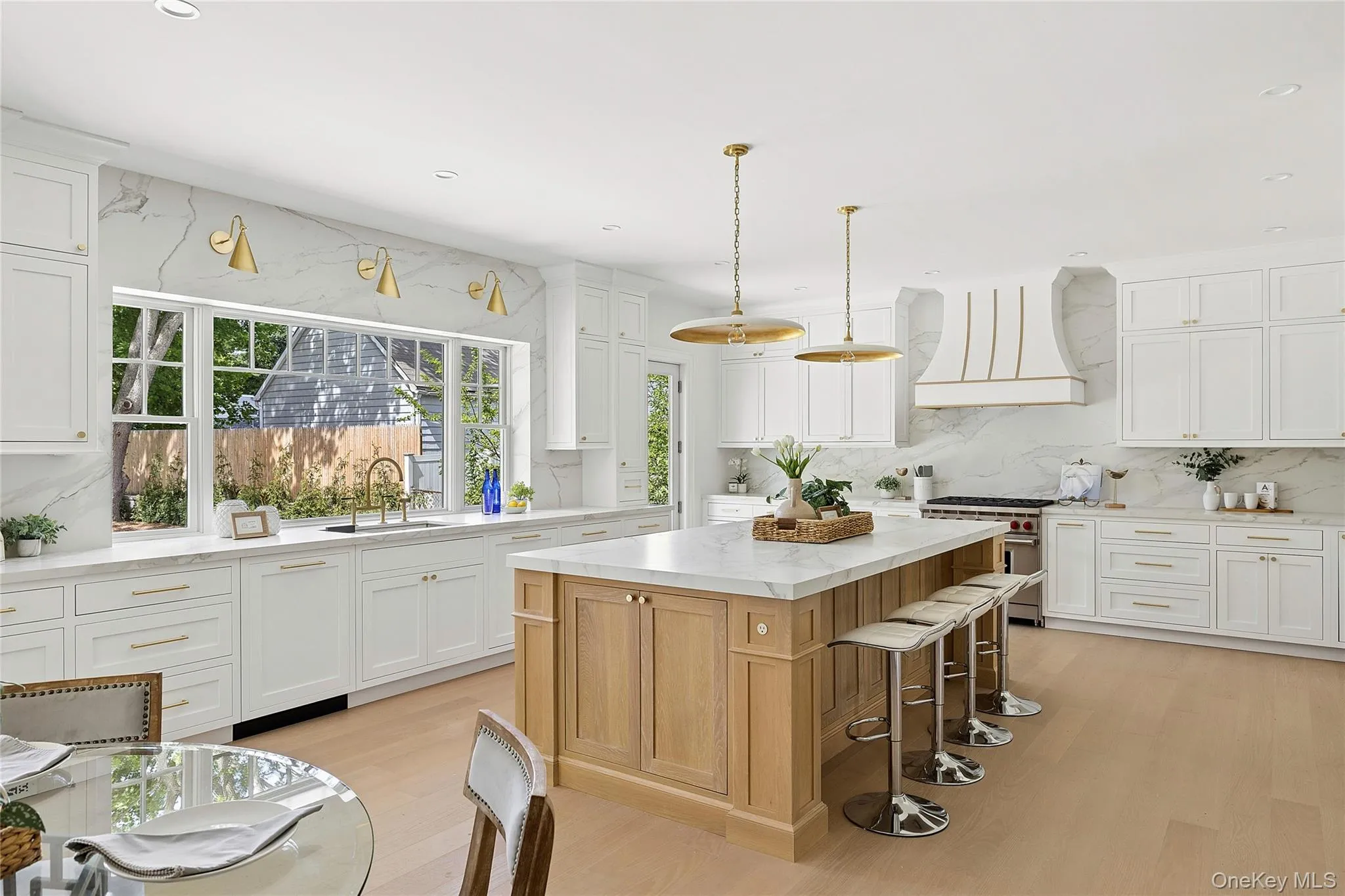 Spacious kitchen featuring an expansive island with a stone countertop, light wood cabinetry, and a built-in range Spacious kitchen featuring an expansive island with a stone countertop, light wood cabinetry, and a built-in range