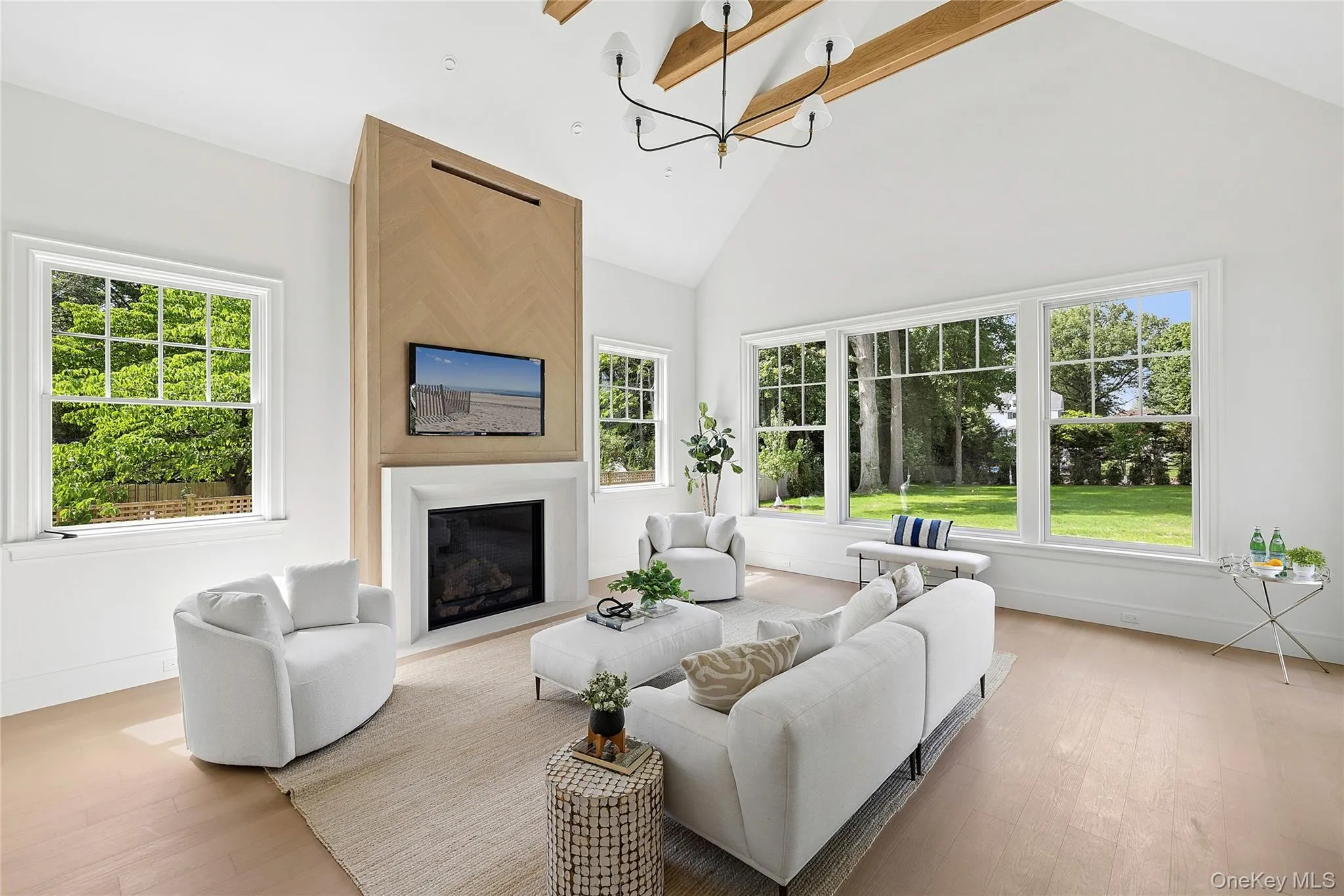 Vaulted ceilings with exposed wood beams define this open living space, featuring a wood-finish flooring Vaulted ceilings with exposed wood beams define this open living space, featuring a wood-finish flooring