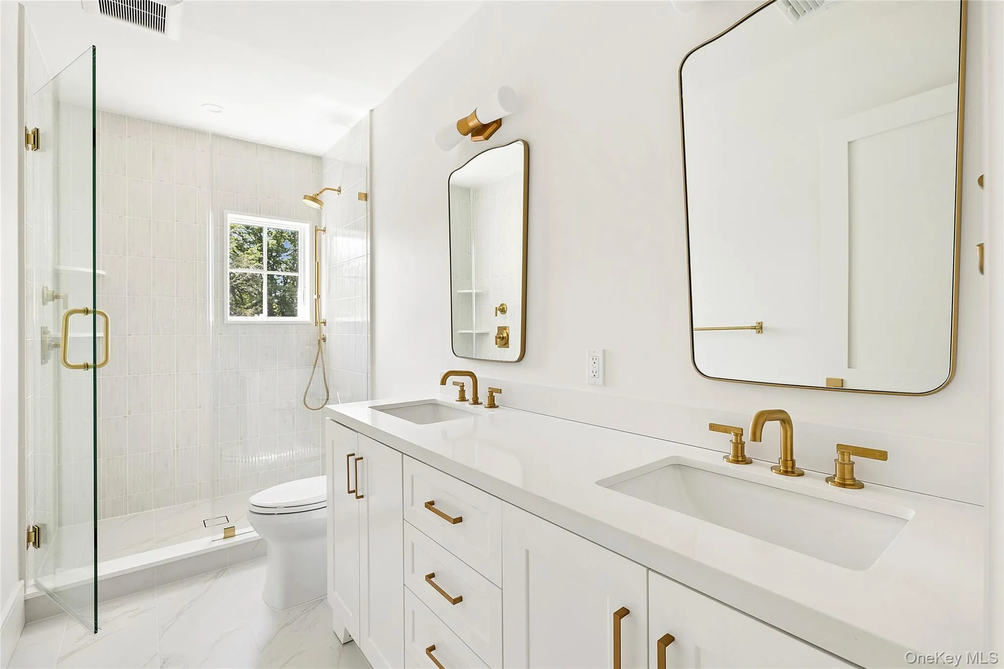 Bathroom featuring a dual vanity with white cabinetry, integrated sinks, and gold-finish fixtures Bathroom featuring a dual vanity with white cabinetry, integrated sinks, and gold-finish fixtures