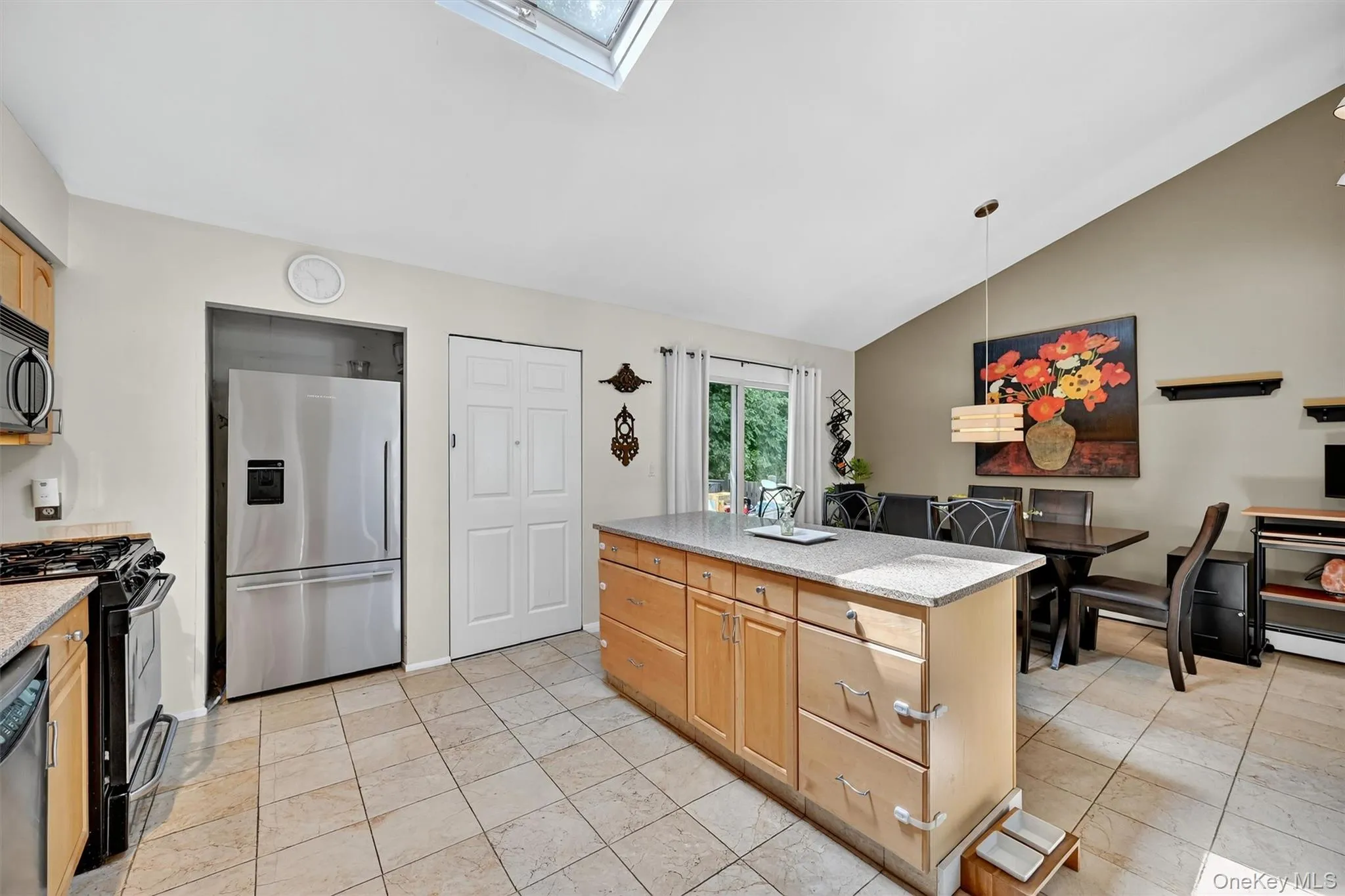 Kitchen featuring a skylight, stainless steel appliances, pendant lighting, vaulted ceiling, and light stone counters Kitchen featuring a skylight, stainless steel appliances, pendant lighting, vaulted ceiling, and light stone counters