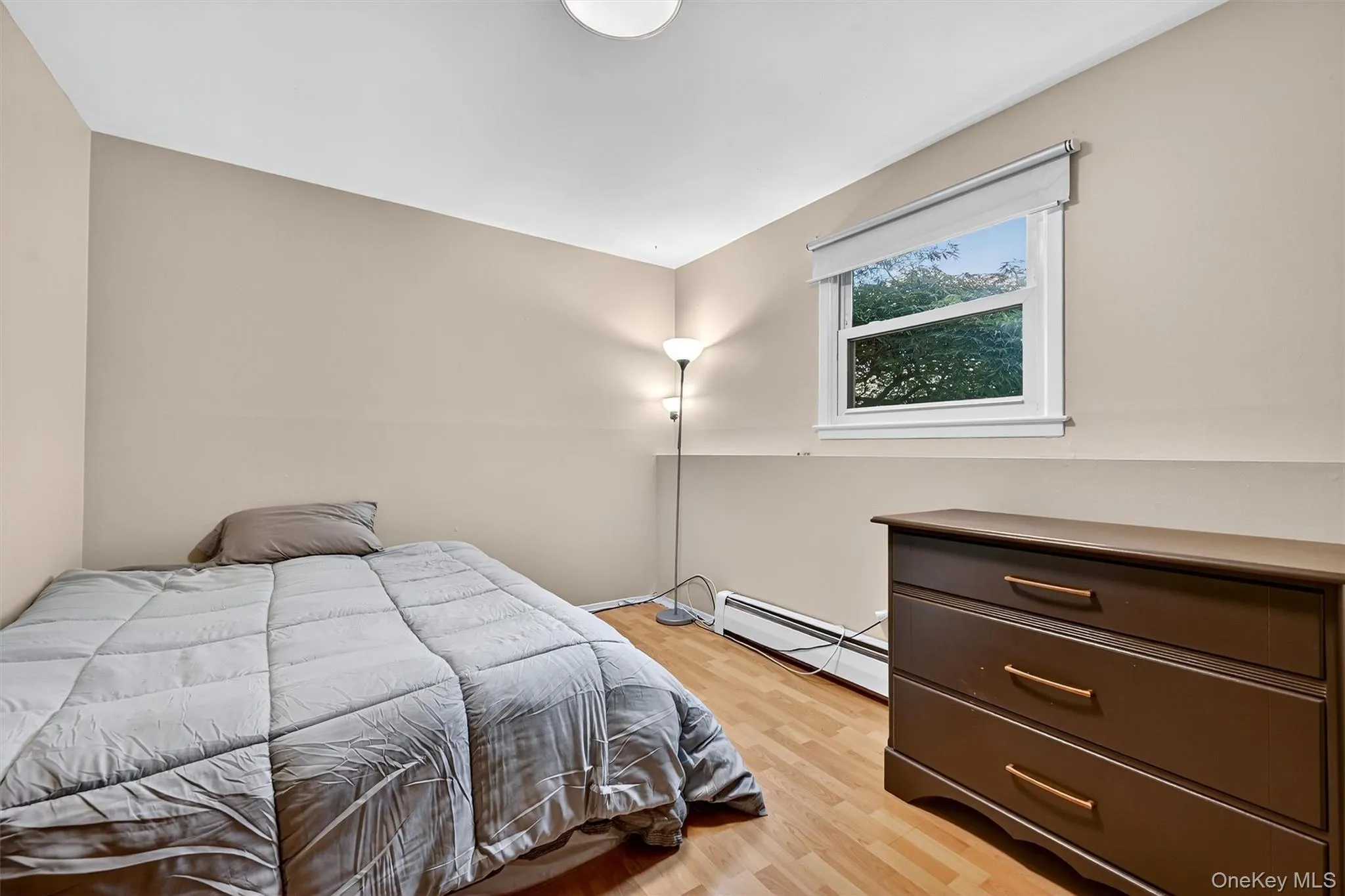 Bedroom featuring baseboard heating and light wood-style flooring Bedroom featuring baseboard heating and light wood-style flooring