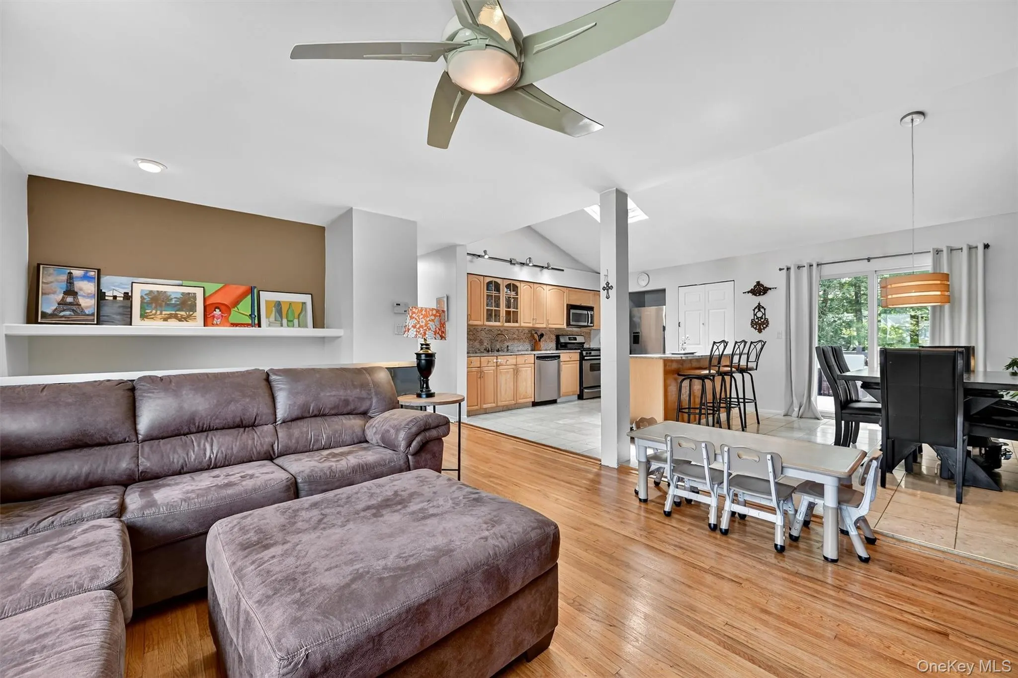 Living area with a ceiling fan, light wood-type flooring, and vaulted ceiling Living area with a ceiling fan, light wood-type flooring, and vaulted ceiling