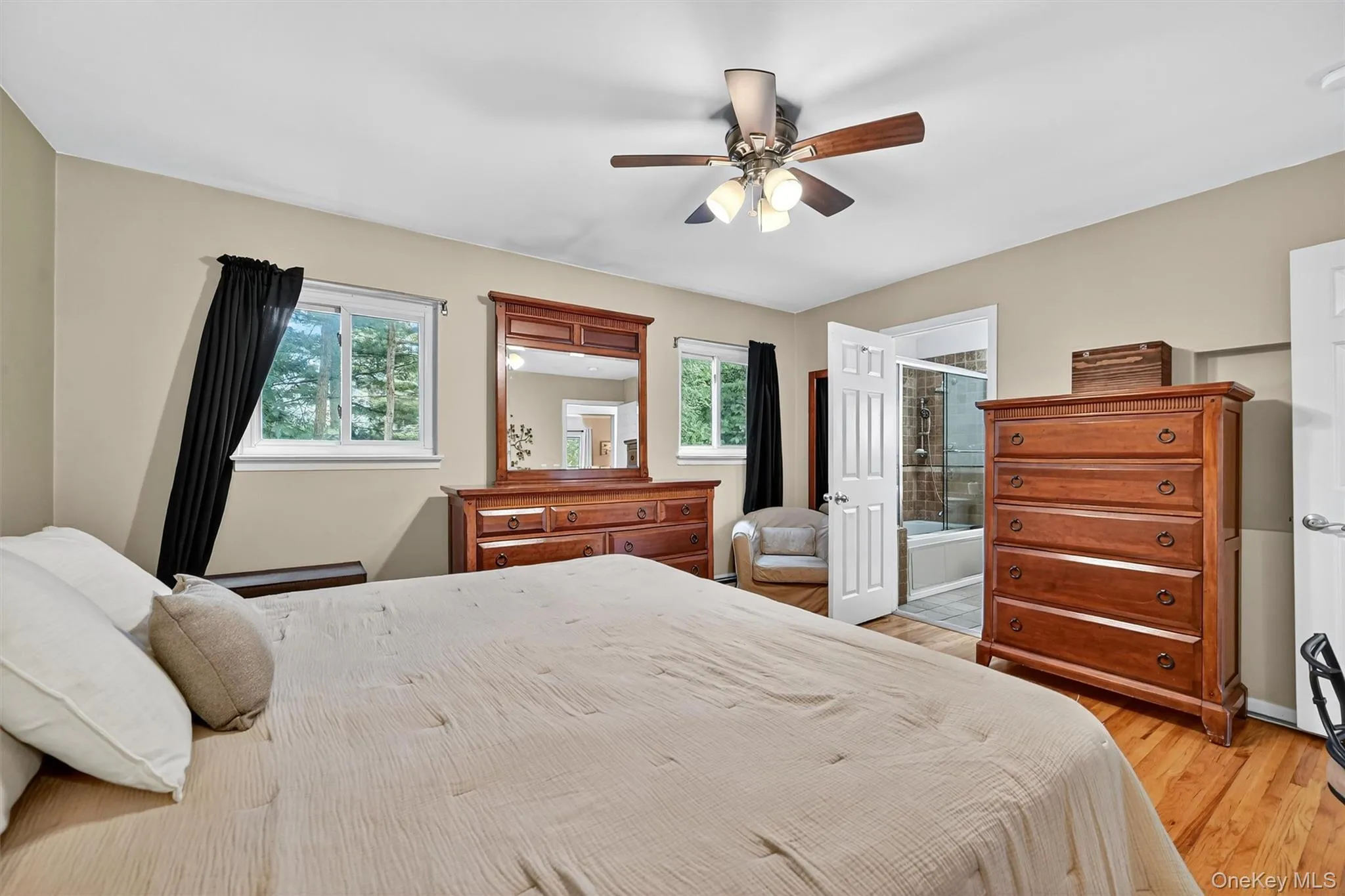 Bedroom with light wood-type flooring, a ceiling fan, and ensuite bath Bedroom with light wood-type flooring, a ceiling fan, and ensuite bath