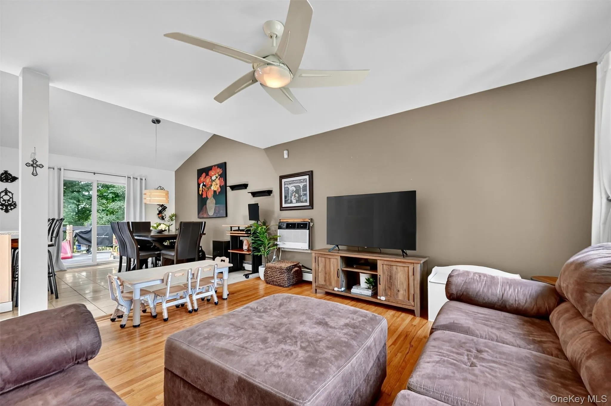 Living room featuring wood finished floors, vaulted ceiling, and a ceiling fan Living room featuring wood finished floors, vaulted ceiling, and a ceiling fan