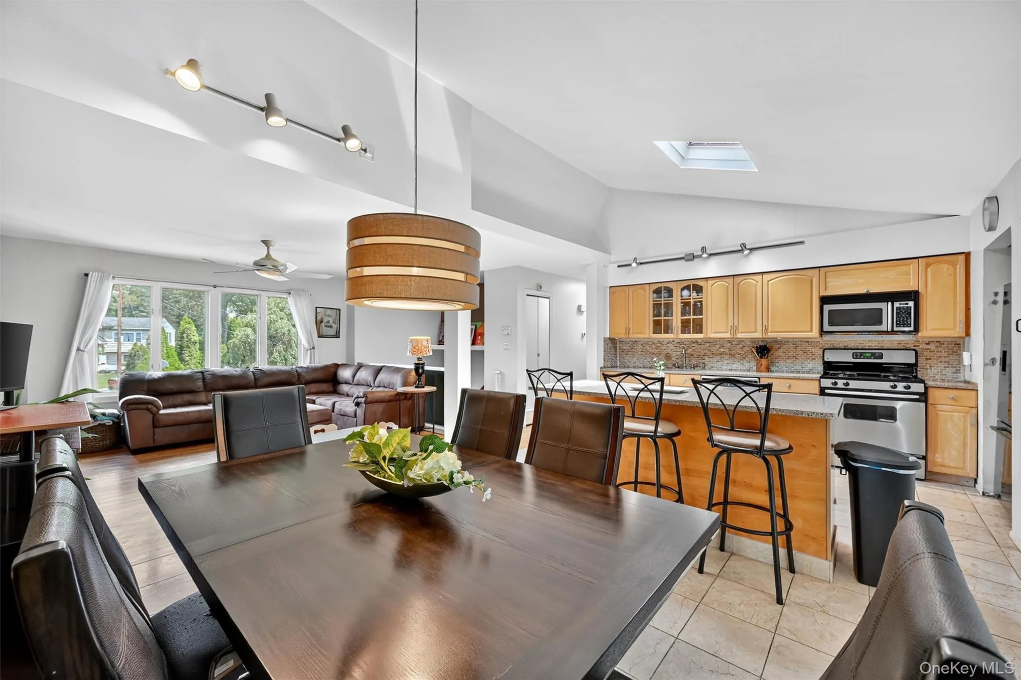 Dining area with vaulted ceiling, light tile patterned floors, a skylight, and ceiling fan Dining area with vaulted ceiling, light tile patterned floors, a skylight, and ceiling fan