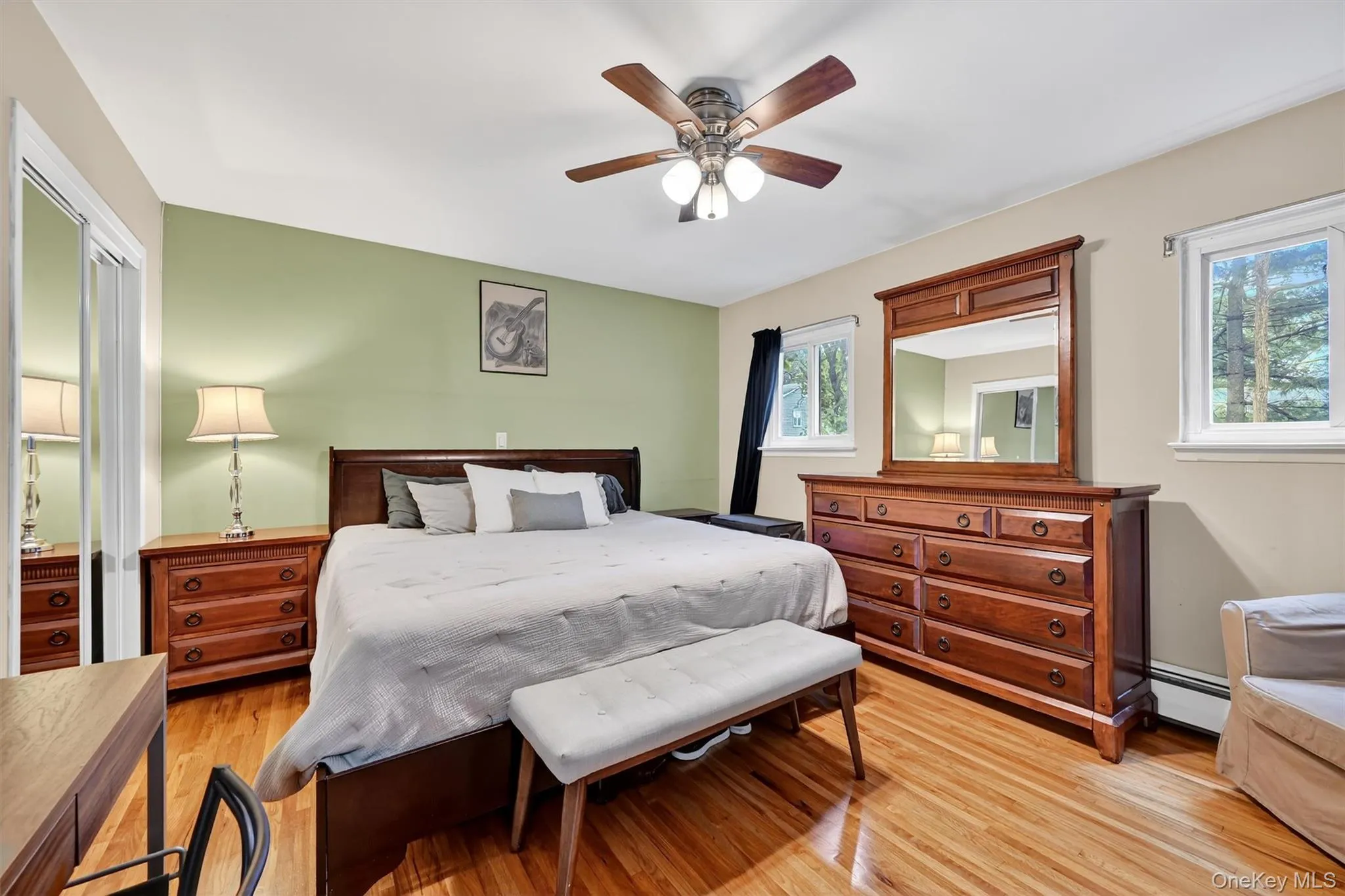 Bedroom with light wood-type flooring, ceiling fan, and baseboard heating Bedroom with light wood-type flooring, ceiling fan, and baseboard heating