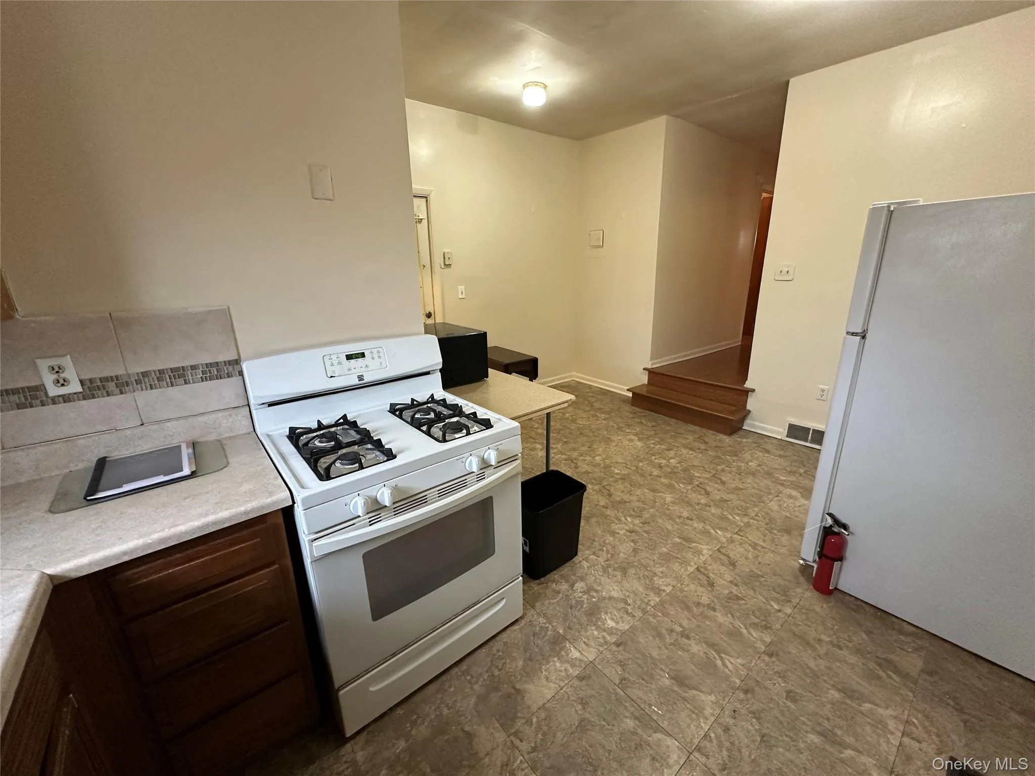 Kitchen with visible vents, white appliances, baseboards, and light countertops Kitchen with visible vents, white appliances, baseboards, and light countertops
