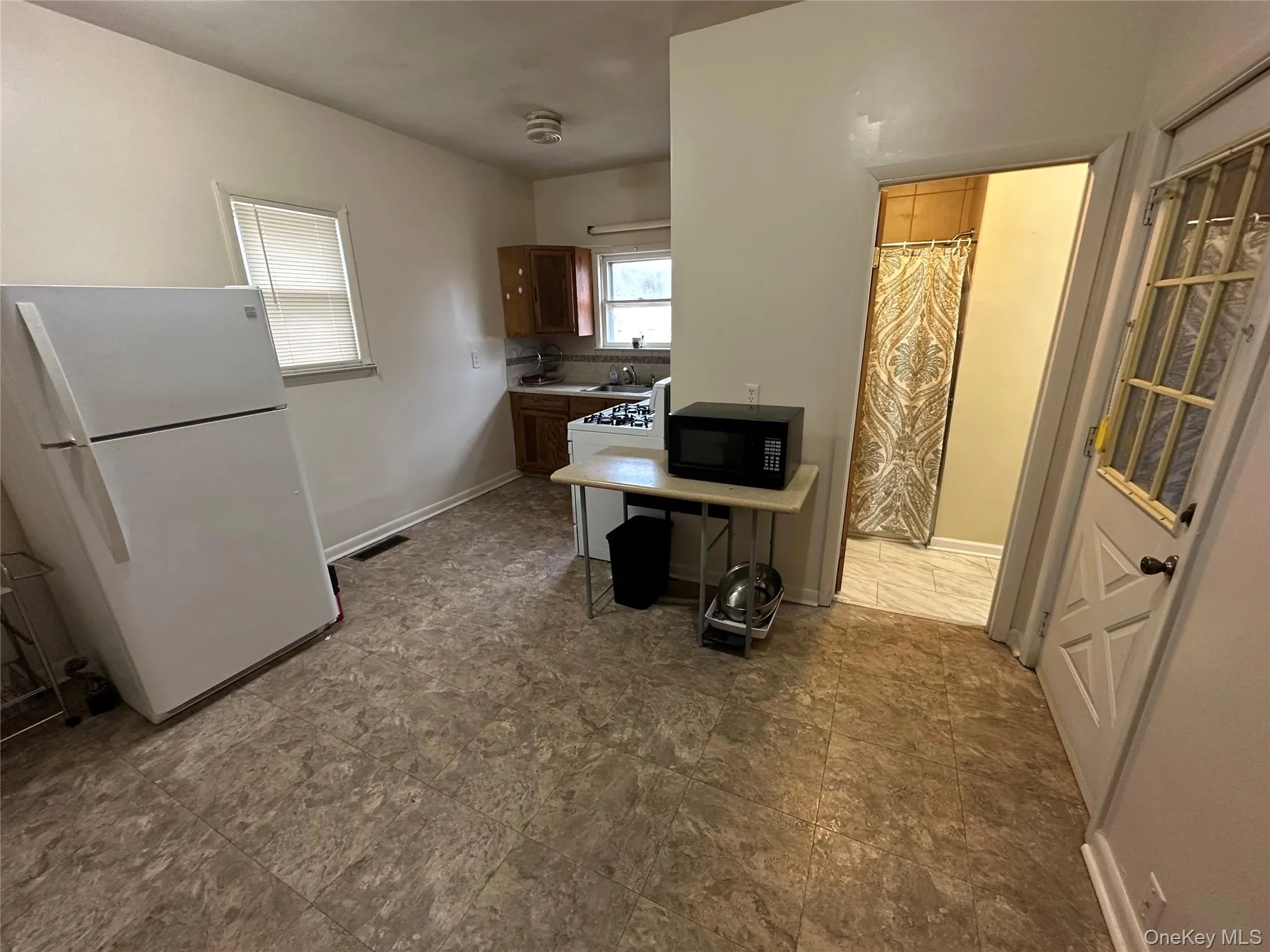 Eat-in kitchen with visible vents, white appliances, light countertops, and baseboards Eat-in kitchen with visible vents, white appliances, light countertops, and baseboards