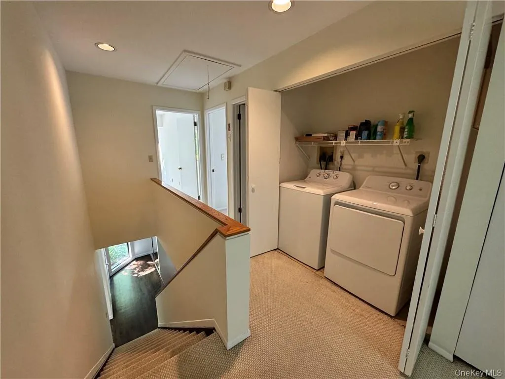 View of second floor landing with stairs showcasing front door with double entry closet. Notice pull down stair for additional attic storage View of second floor landing with stairs showcasing front door with double entry closet. Notice pull down stair for additional attic storage