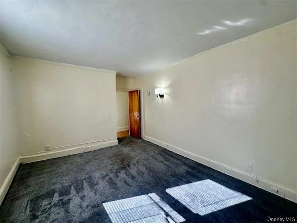 Spare room featuring dark colored carpet and crown molding Spare room featuring dark colored carpet and crown molding
