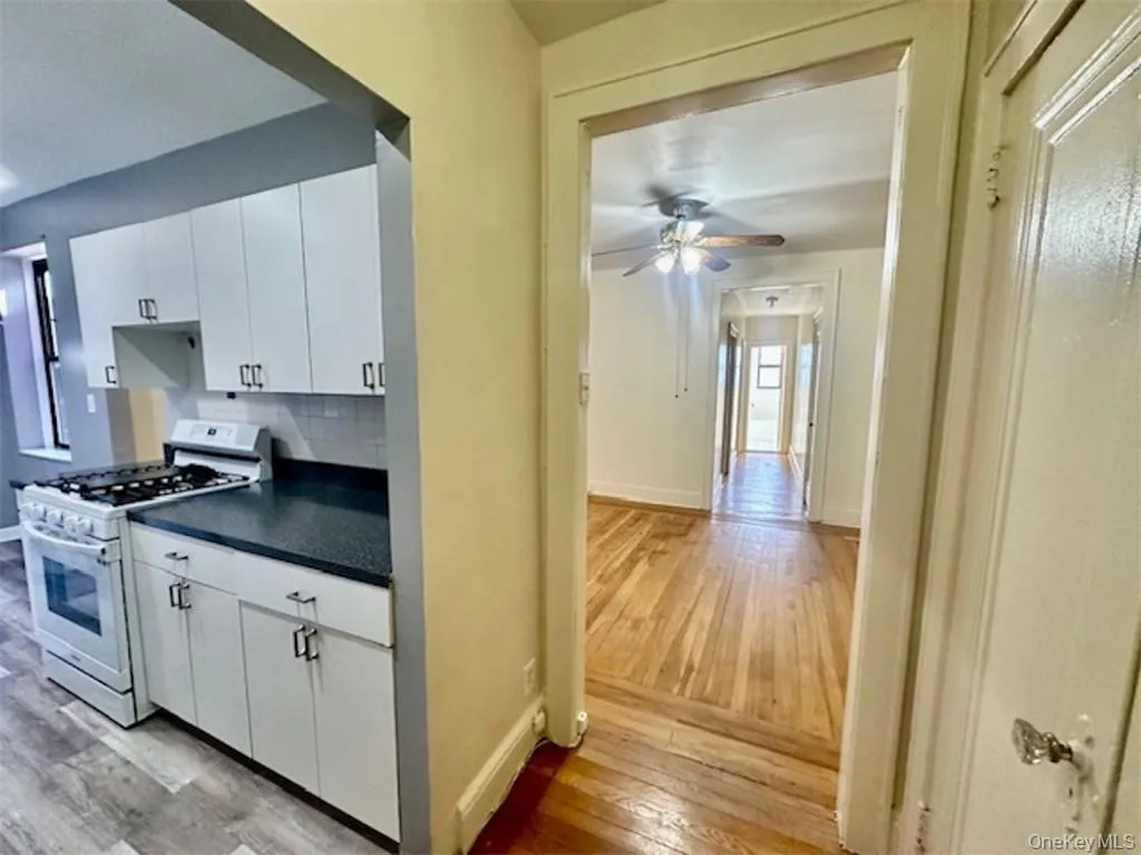 Kitchen featuring white cabinetry, light hardwood / wood-style flooring, gas range gas stove, and backsplash Kitchen featuring white cabinetry, light hardwood / wood-style flooring, gas range gas stove, and backsplash