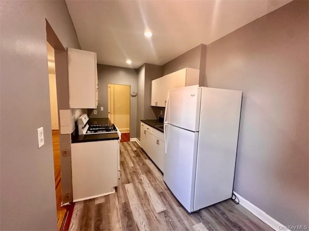 Kitchen featuring white cabinets, white appliances, and light hardwood / wood-style flooring Kitchen featuring white cabinets, white appliances, and light hardwood / wood-style flooring