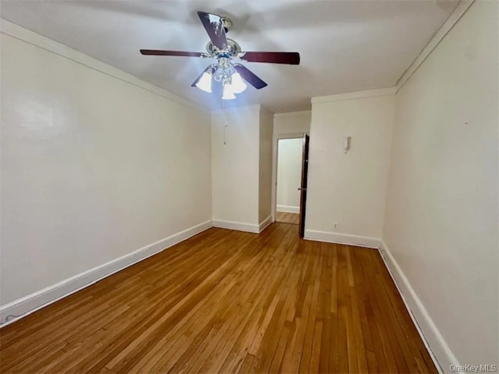 Spare room with ceiling fan, light wood-type flooring, and crown molding Spare room with ceiling fan, light wood-type flooring, and crown molding