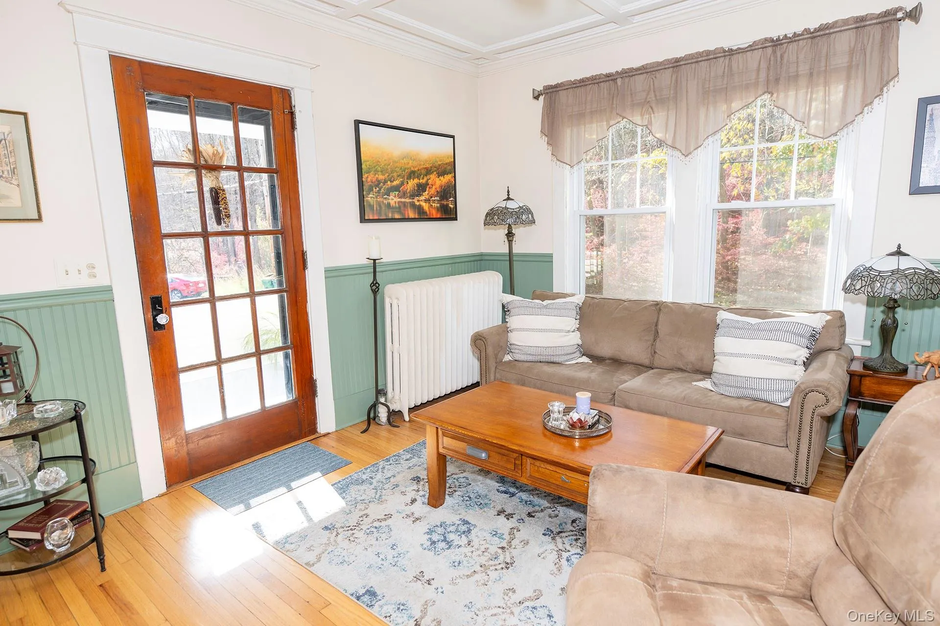 Living room featuring healthy amount of natural light, hardwood / wood-style floors, and glass door to side covered porch Living room featuring healthy amount of natural light, hardwood / wood-style floors, and glass door to side covered porch