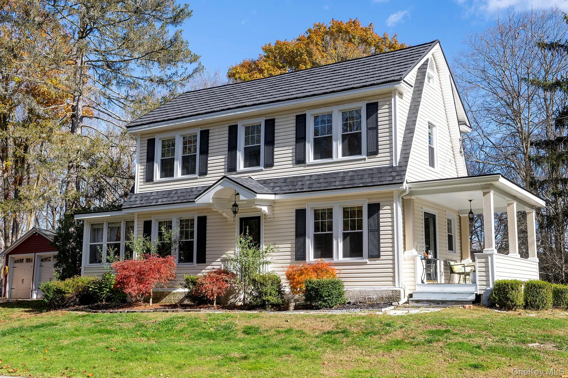 View of front of property with a front yard, covered porch, and a garage View of front of property with a front yard, covered porch, and a garage