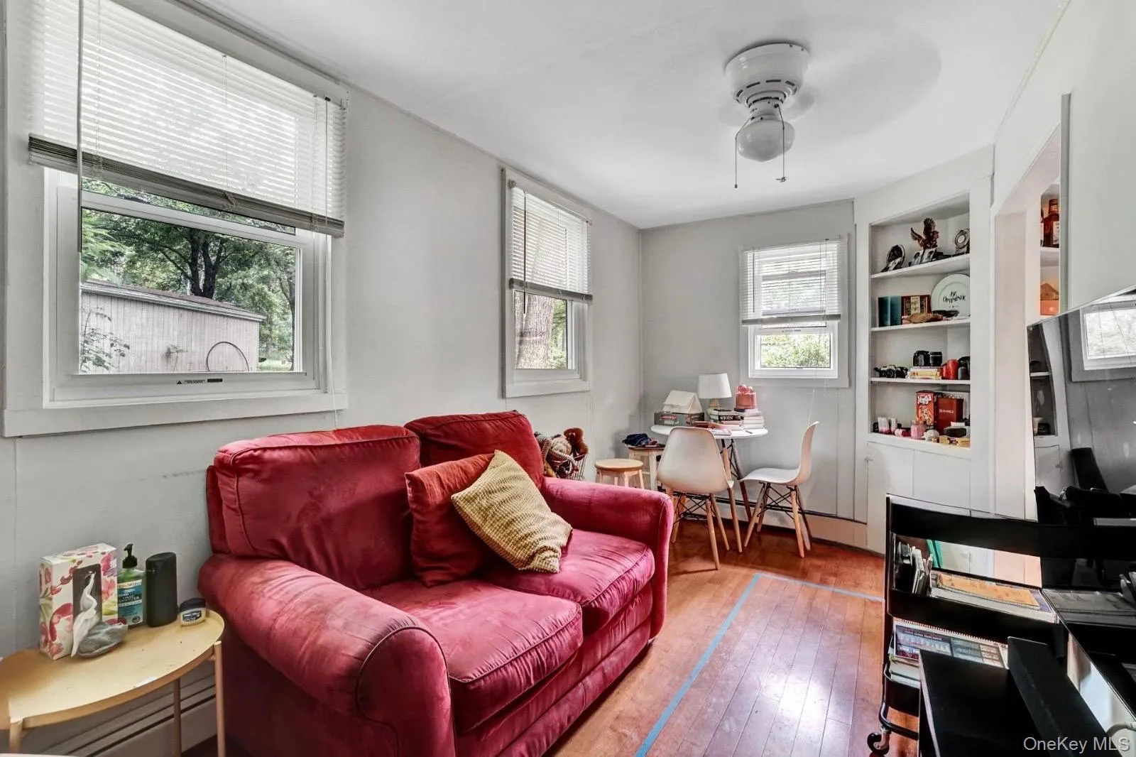 Living area featuring hardwood / wood-style floors, built in features, ceiling fan, and a baseboard radiator Living area featuring hardwood / wood-style floors, built in features, ceiling fan, and a baseboard radiator