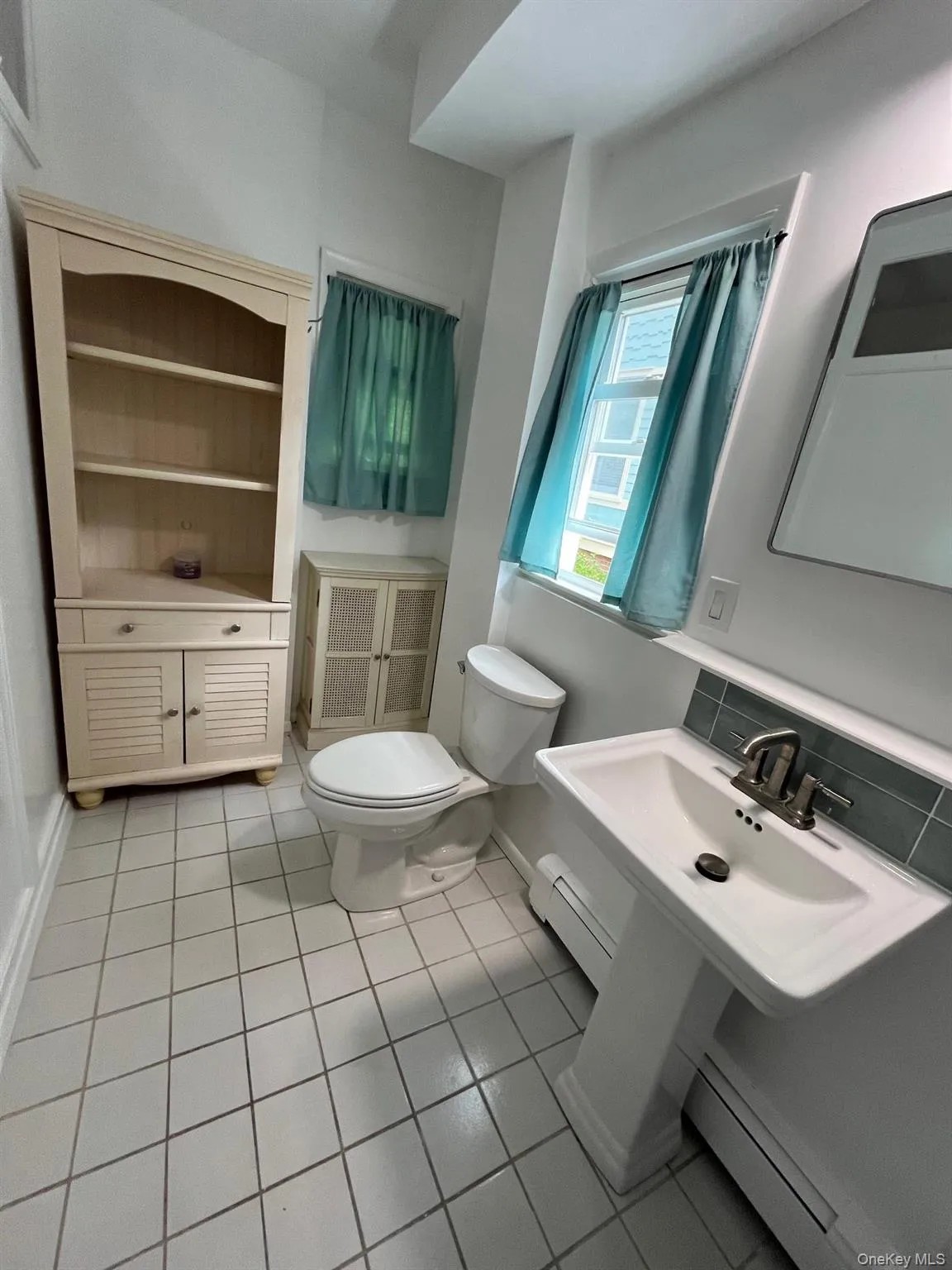 Bathroom with baseboards, tile patterned flooring, baseboard heating, and toilet Bathroom with baseboards, tile patterned flooring, baseboard heating, and toilet