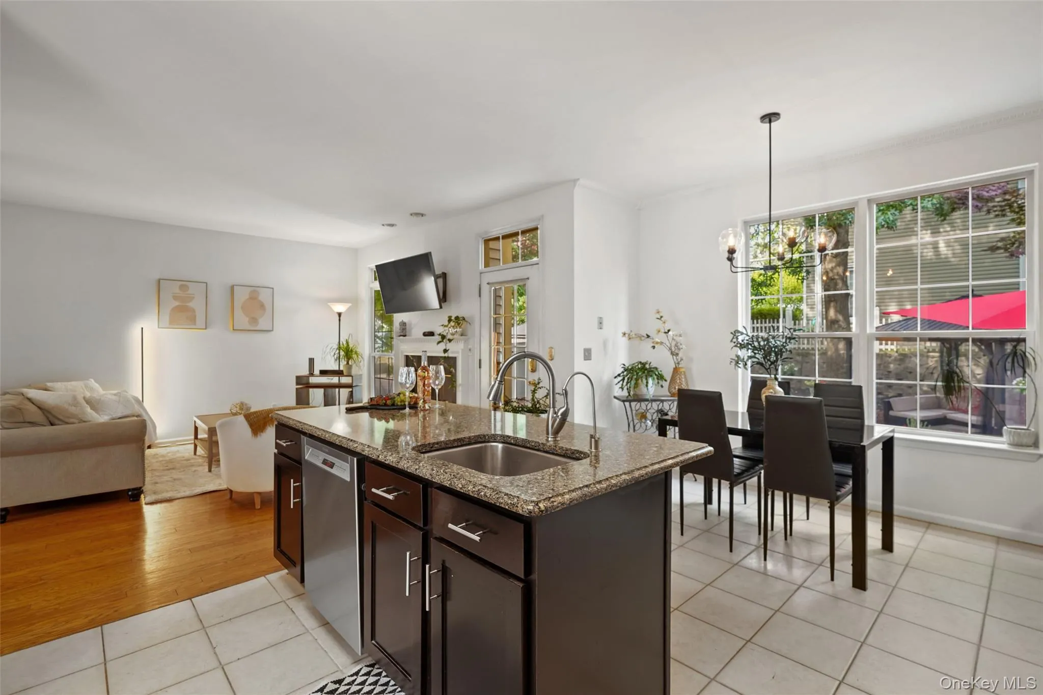 Kitchen island featuring a granite countertop, stainless steel sink, and dark wood cabinetry Kitchen island featuring a granite countertop, stainless steel sink, and dark wood cabinetry