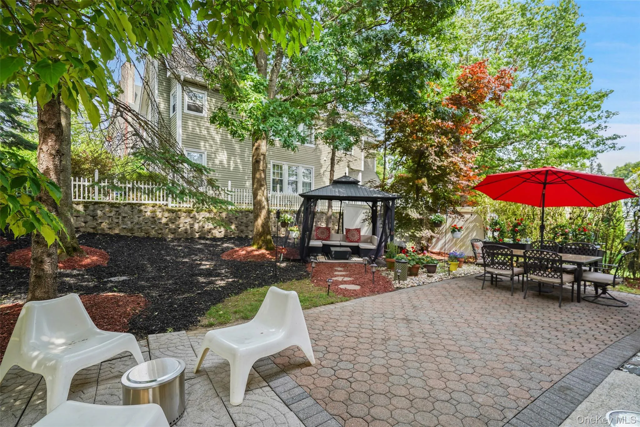 Expansive paver patio bordered by mature trees and landscaped areas Expansive paver patio bordered by mature trees and landscaped areas