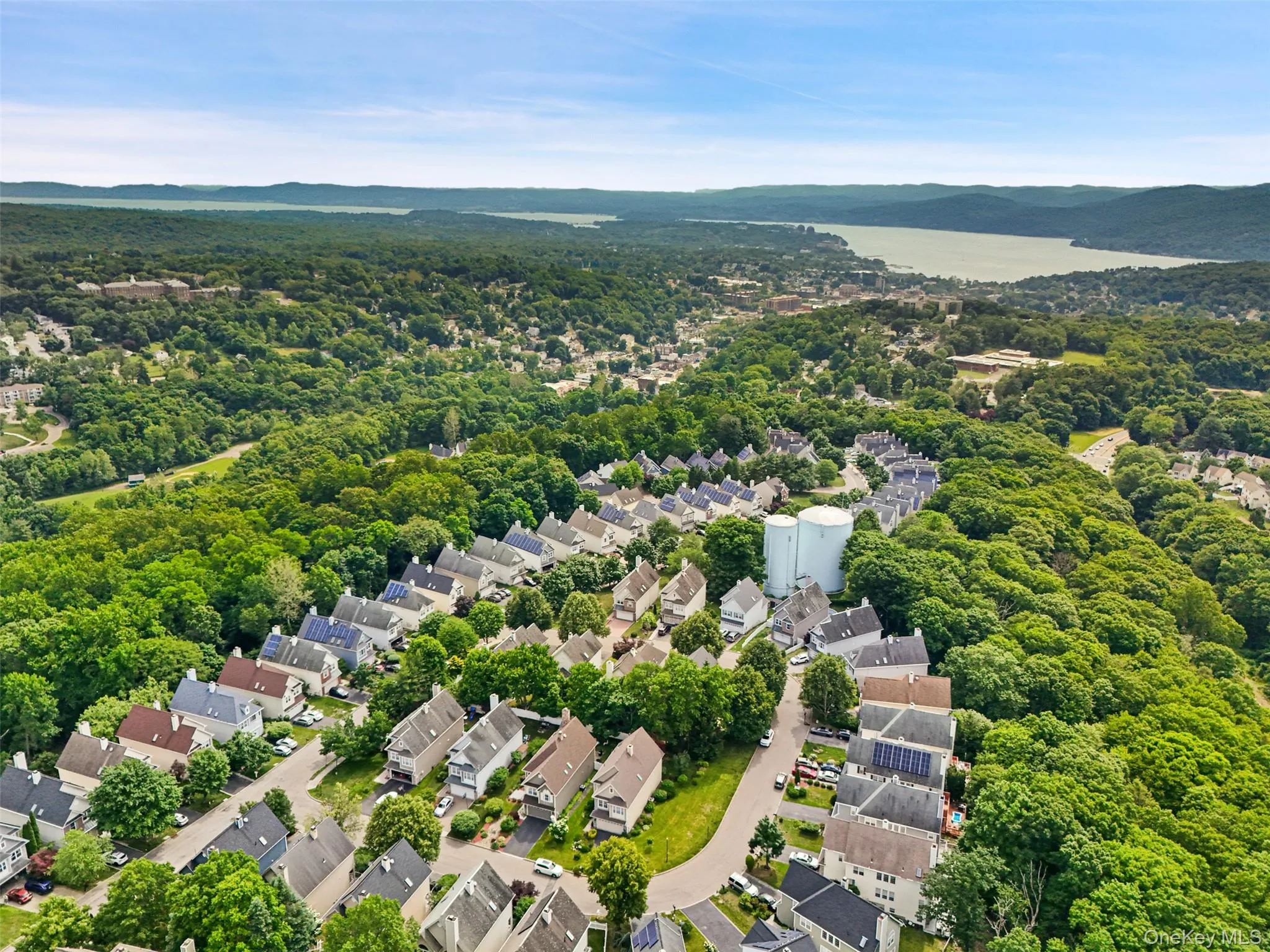 Aerial perspective showcasing a residential community nestled within lush green landscapes with Manhattan in the distance. Aerial perspective showcasing a residential community nestled within lush green landscapes with Manhattan in the distance.