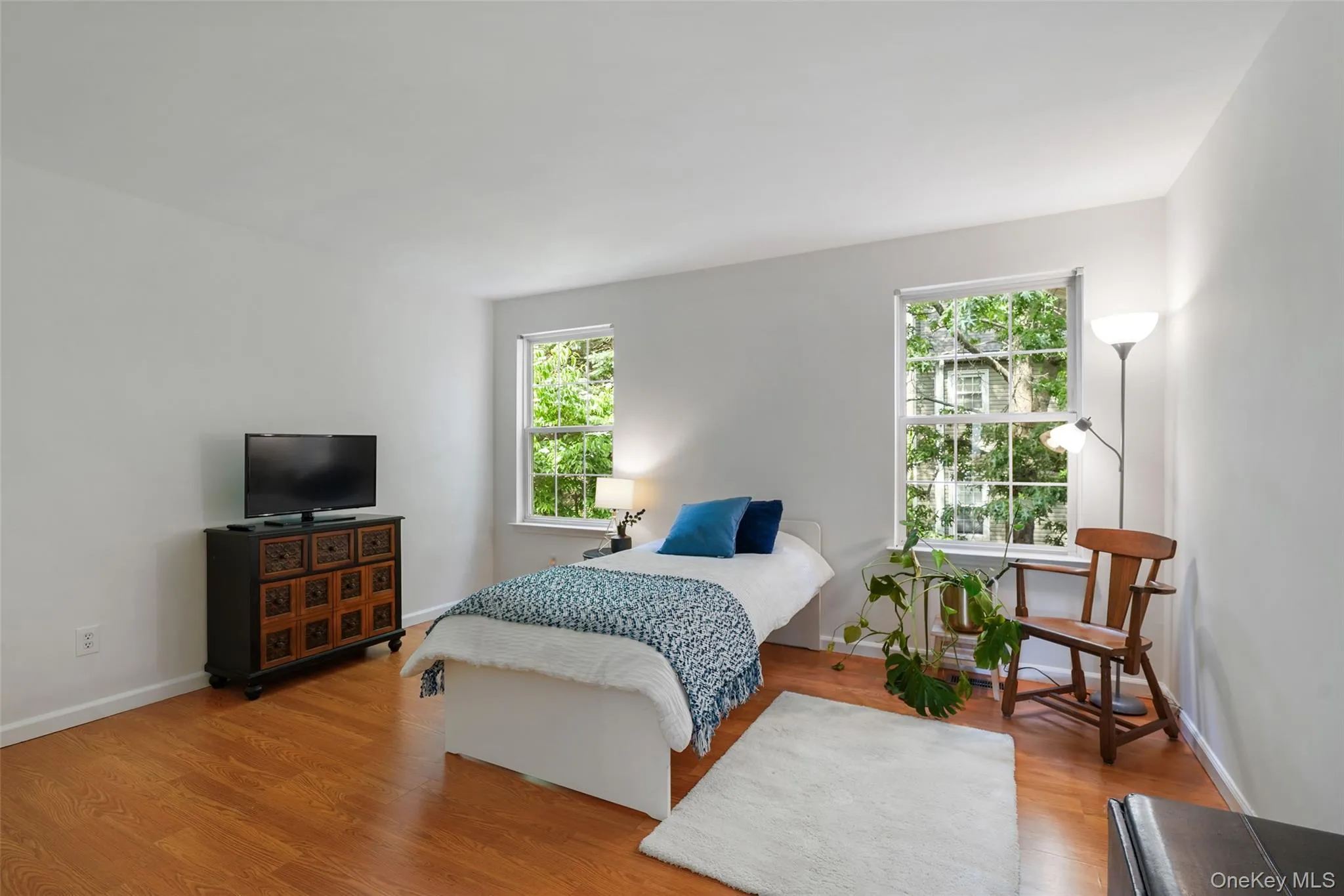 Bright room featuring two windows, wood-finish flooring, and double closet Bright room featuring two windows, wood-finish flooring, and double closet