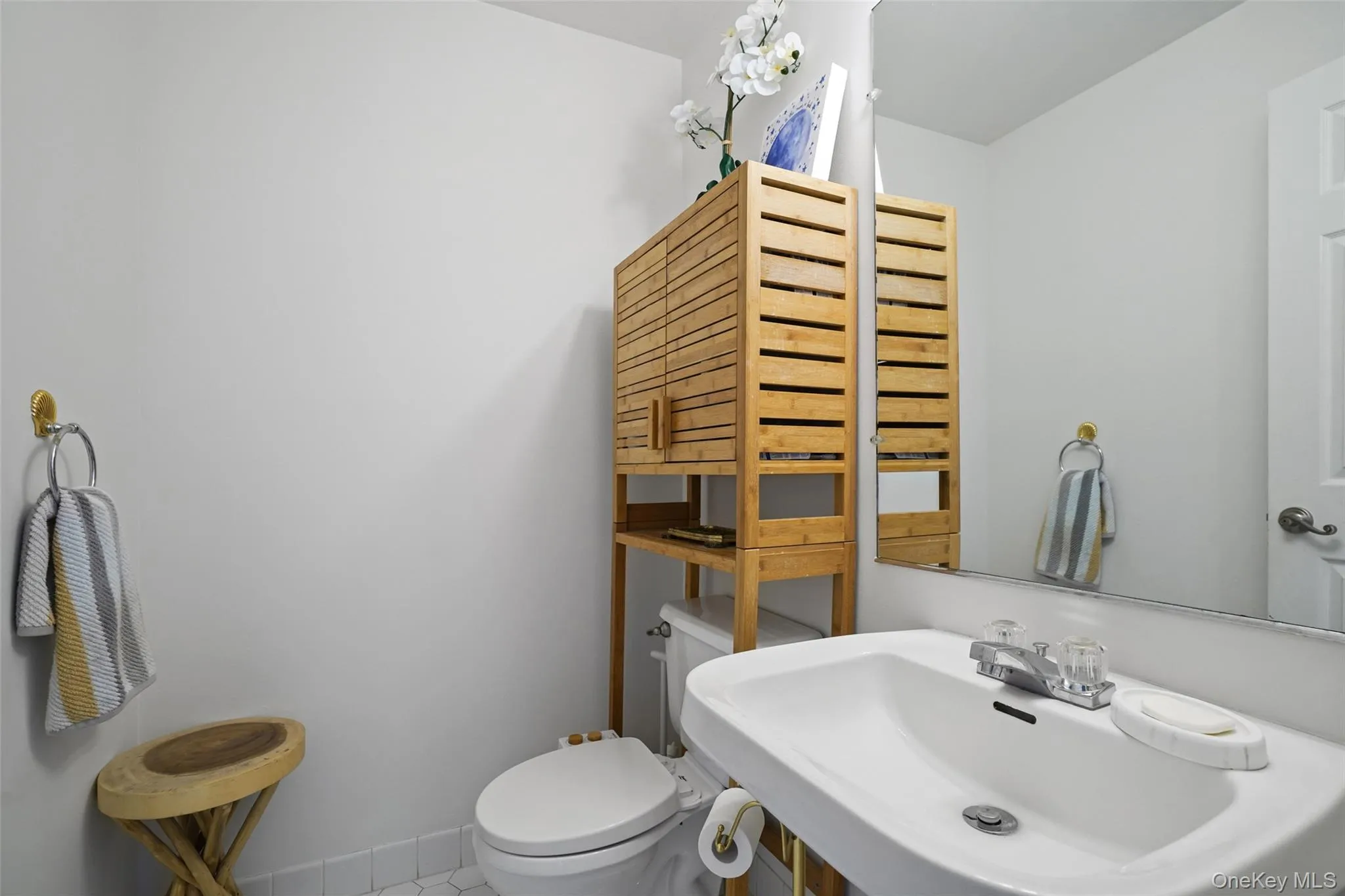 Pedestal sink with chrome faucet, white toilet, and hexagon tile flooring Pedestal sink with chrome faucet, white toilet, and hexagon tile flooring