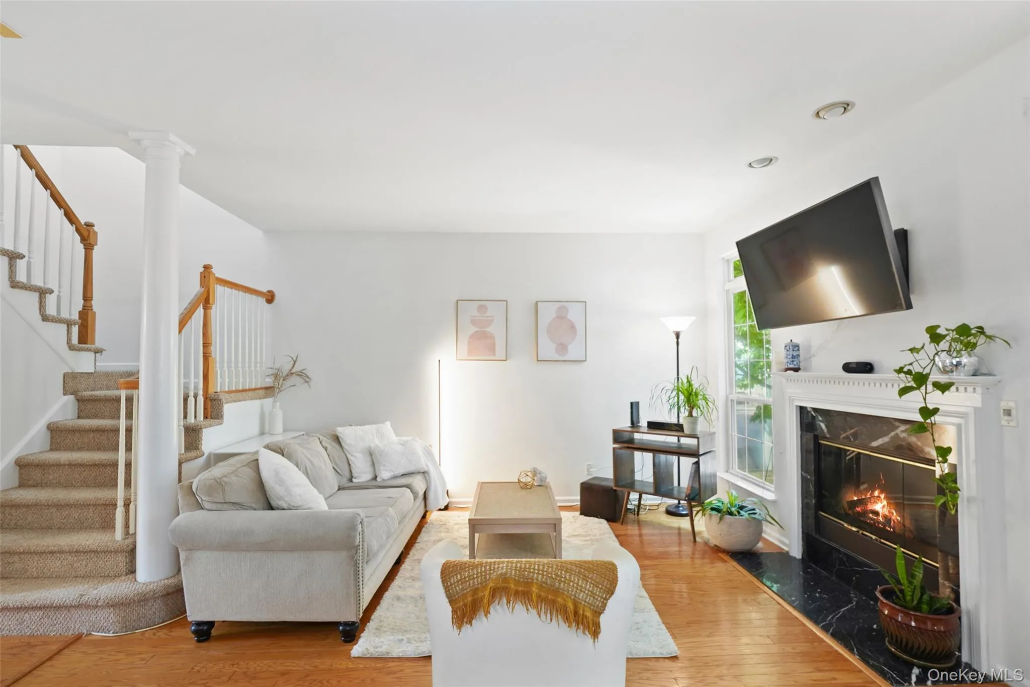 Living area featuring wood-finish flooring and a carpeted staircase with wood handrails Living area featuring wood-finish flooring and a carpeted staircase with wood handrails